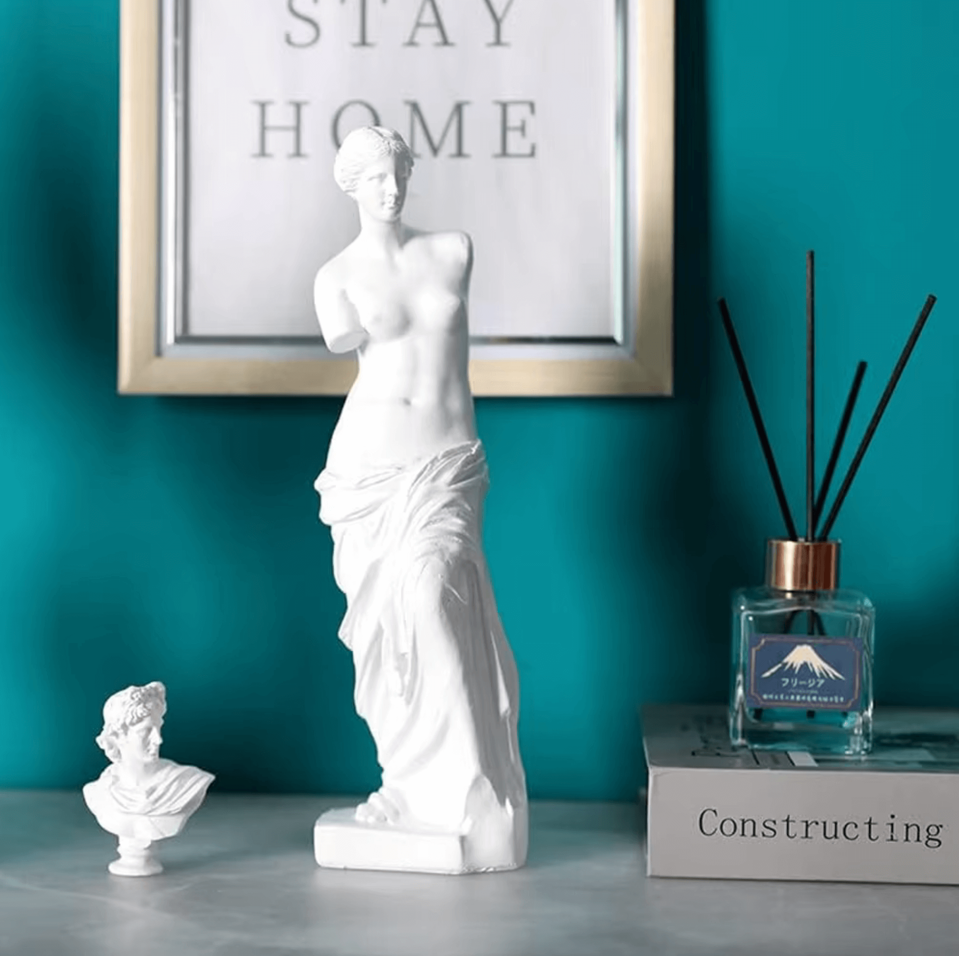 Venus de Milo sculpture enhancing a chic room décor with timeless Greek elegance; framed art and diffuser in background.