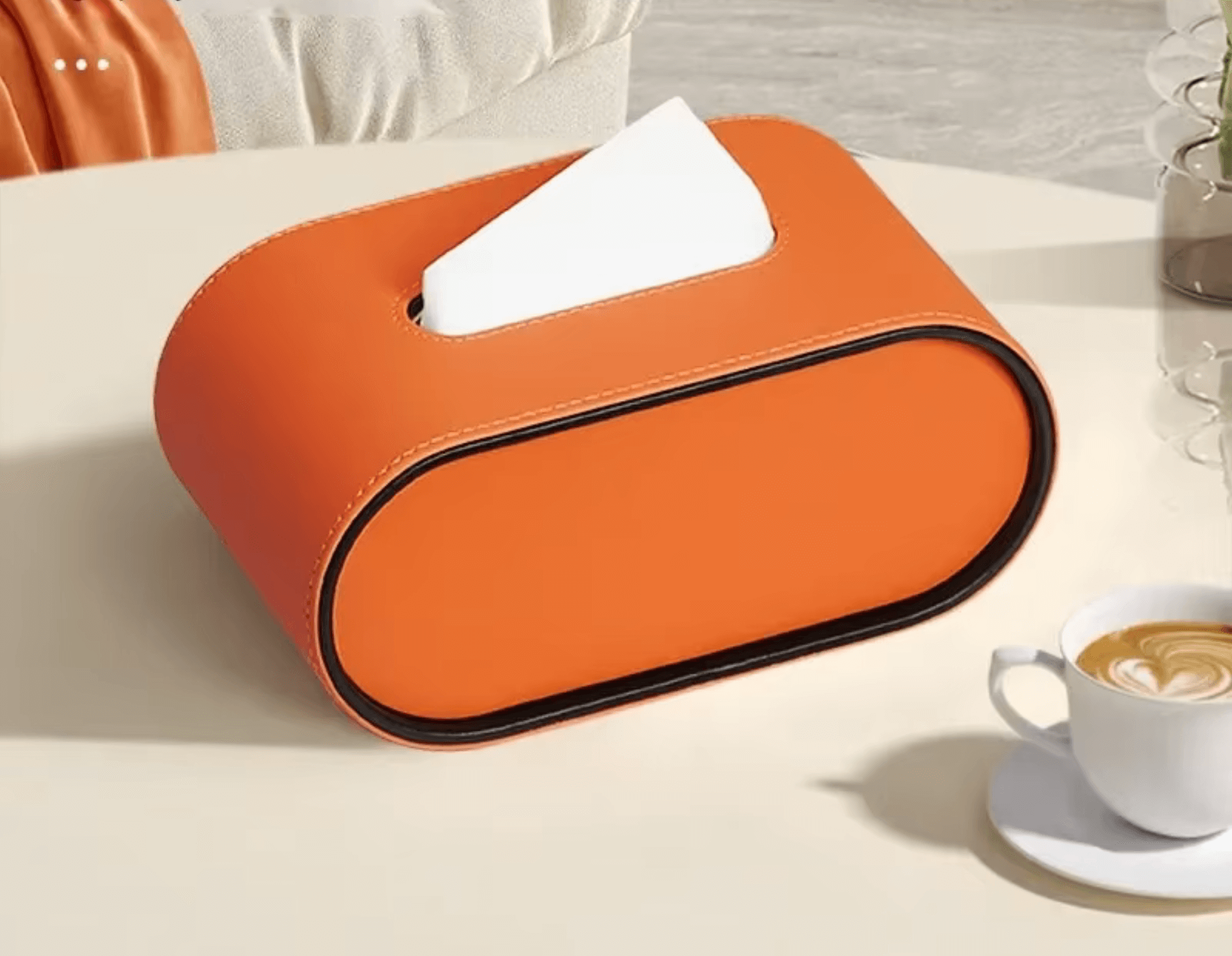 Elegante Leder-Taschentuchbox in ovalem Design auf weißem Tisch neben einer Kaffeetasse, ideal für stilvolle Organisation.