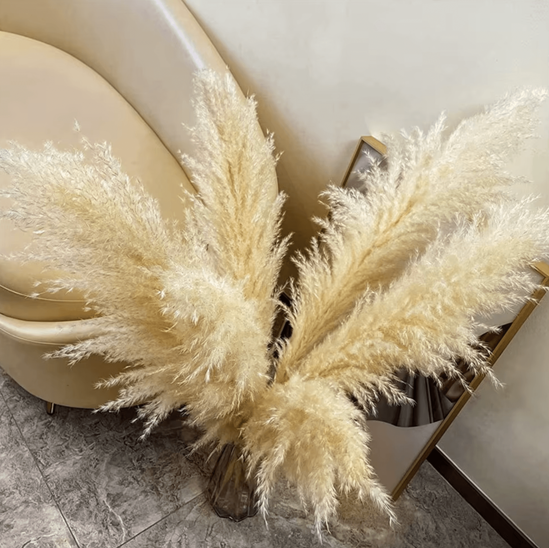 Natürliche Pampasgras-Dekoration vor beigem Sessel, verleiht Boho-Charme und zeitlose Eleganz für luxuriöses Interieur.