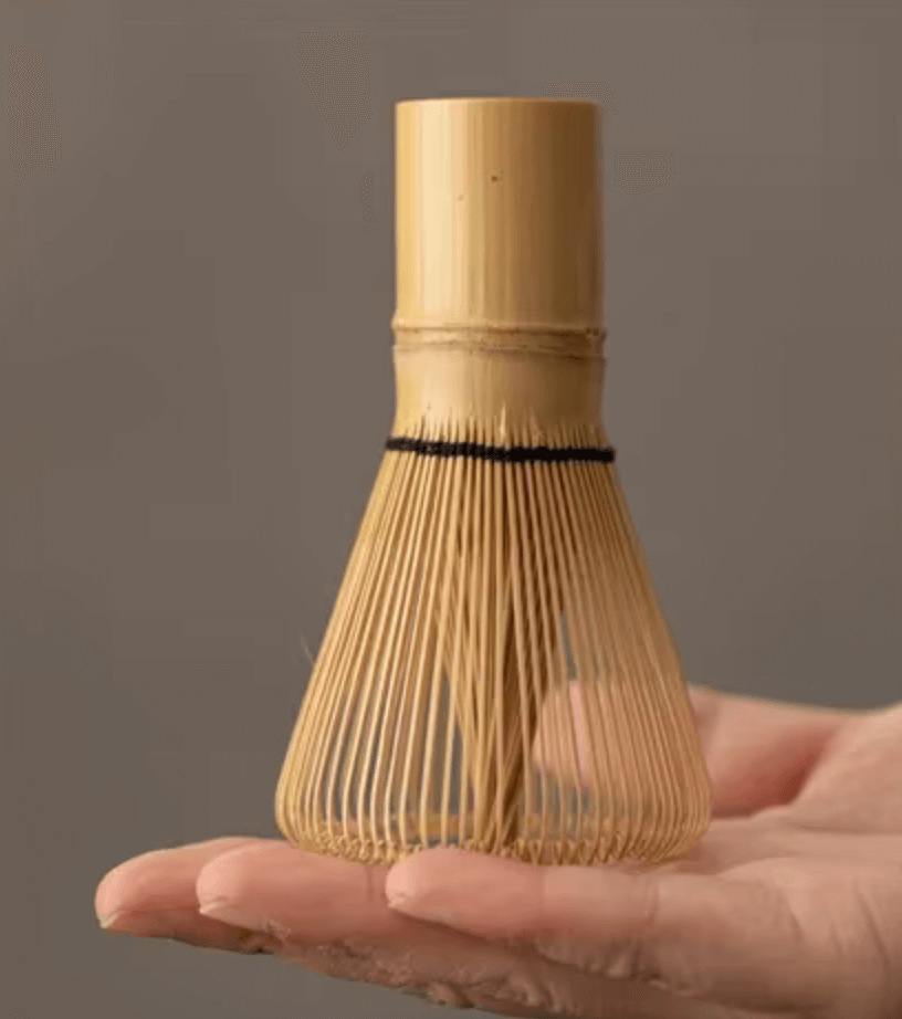 Hand holding bamboo Matcha whisk (Chasen) from Japanisches Matcha-Set for traditional tea ceremony at home.