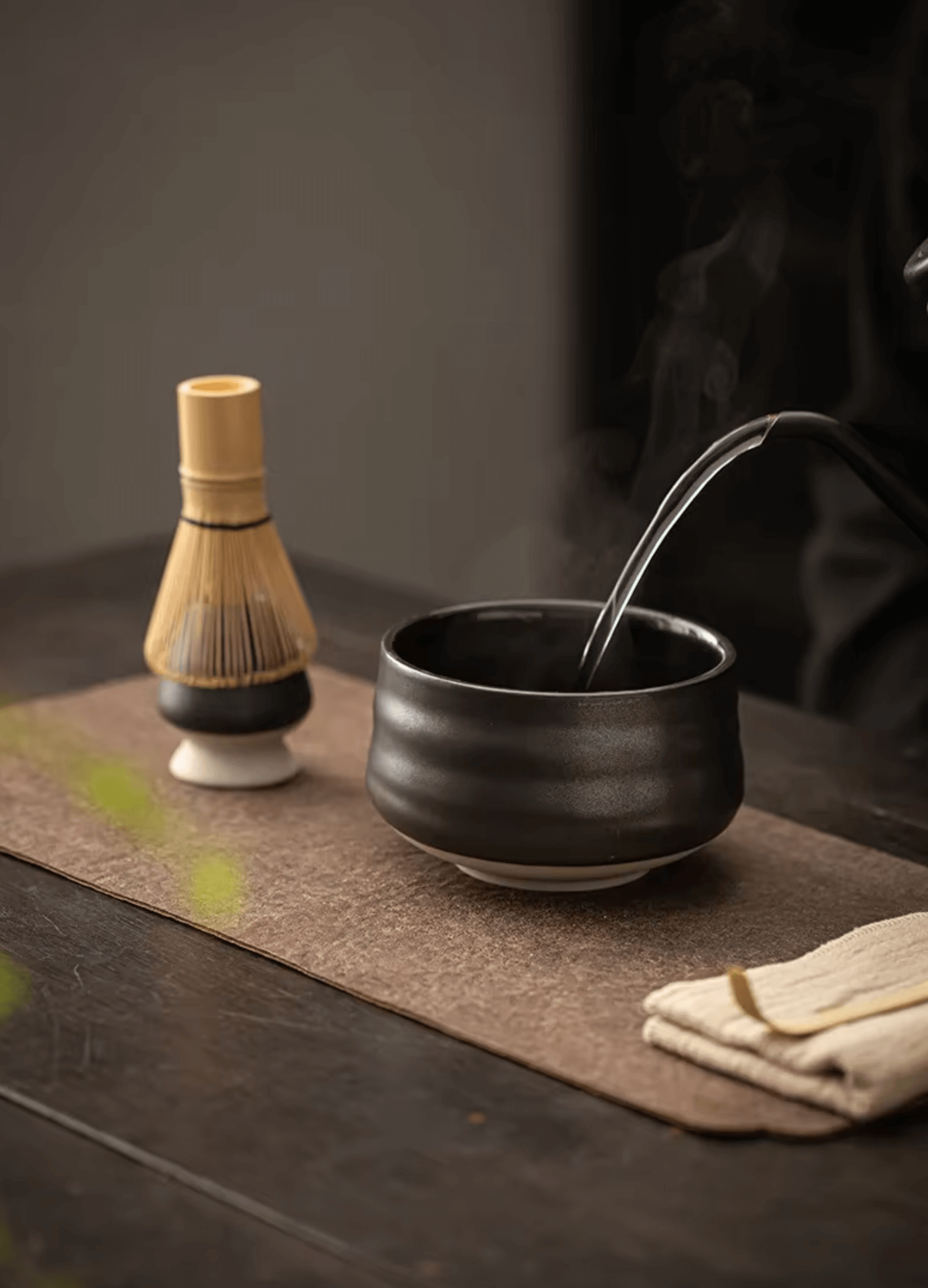 Japanisches Matcha-Set mit Bambus-Schneebesen und Keramikschale für traditionelle Teezeremonie auf rustikalem Holztisch.