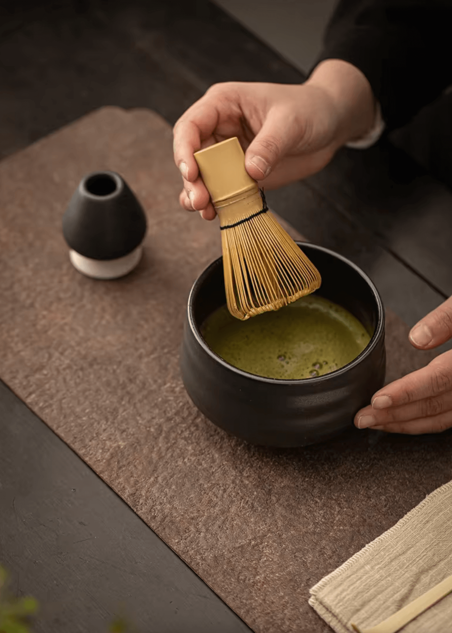 Preparing matcha tea with bamboo whisk for traditional Japanese tea ceremony.