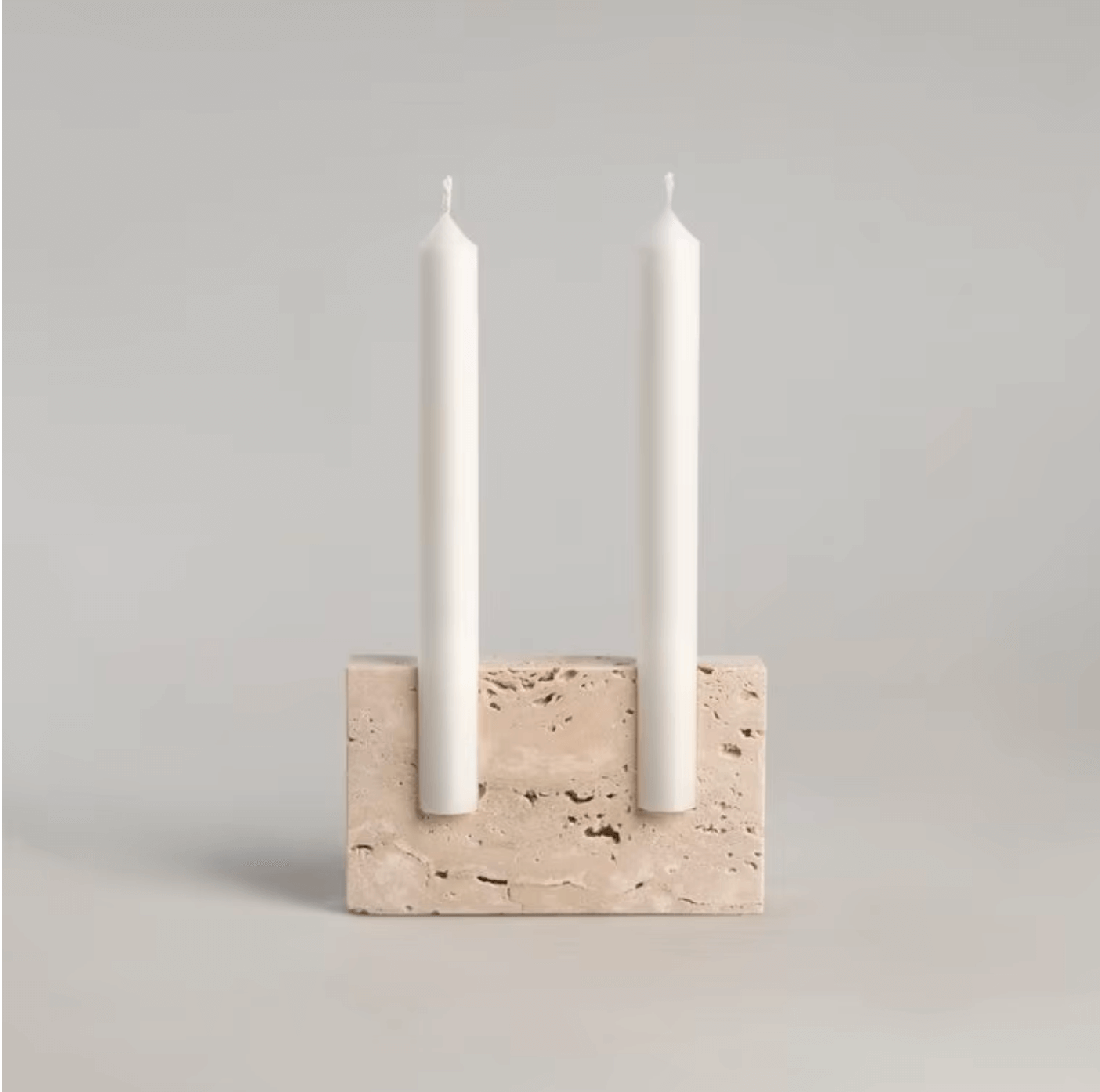 Eleganter Kerzenhalter aus Travertin-Marmor mit zwei weißen Kerzen, ideal für nordischen Minimalismus und stilvolle Dekoration.
