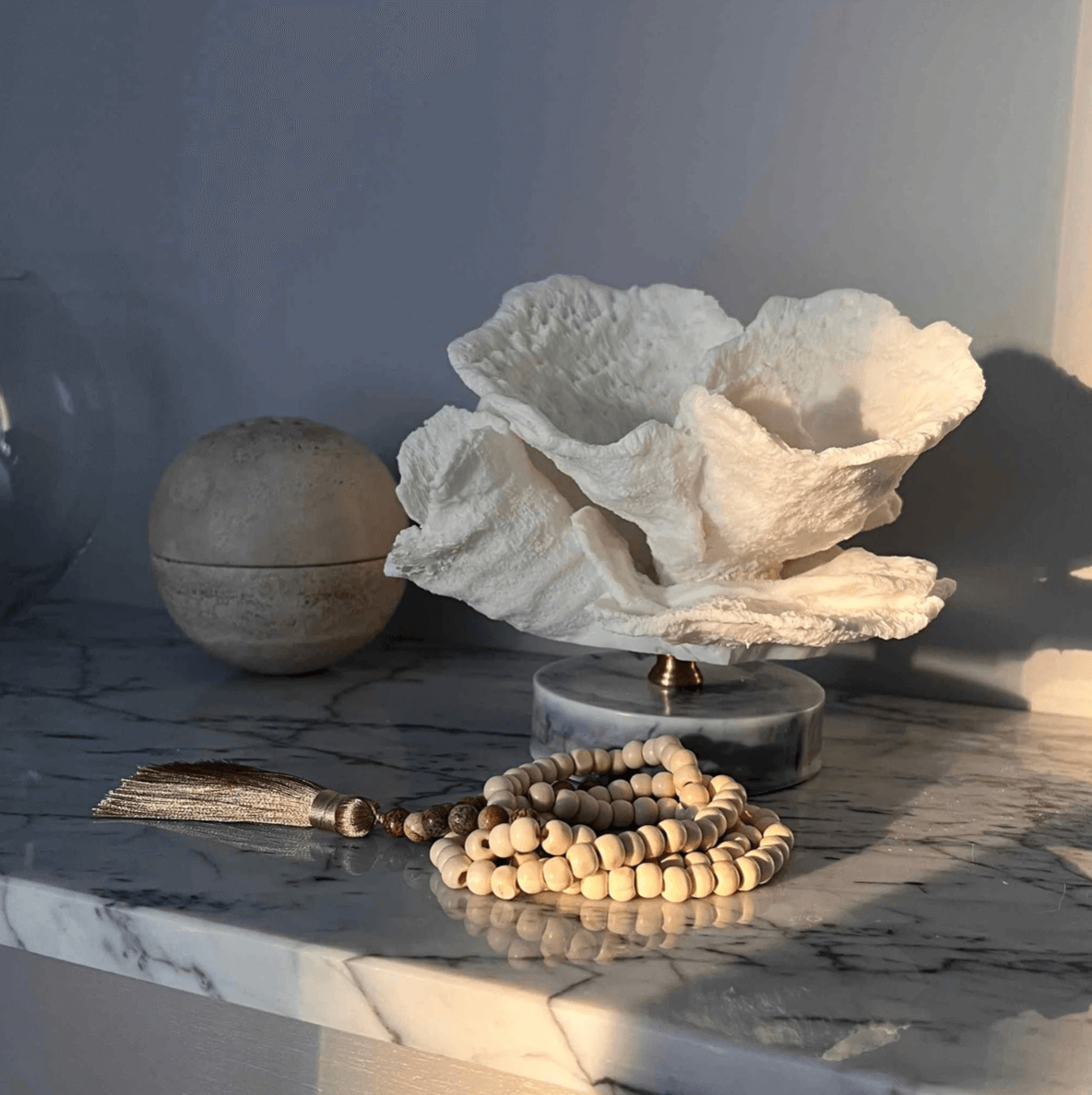 Korallenornament auf Marmorsockel, minimalistisches Design mit Holzperlen und Quaste auf Marmoroberfläche