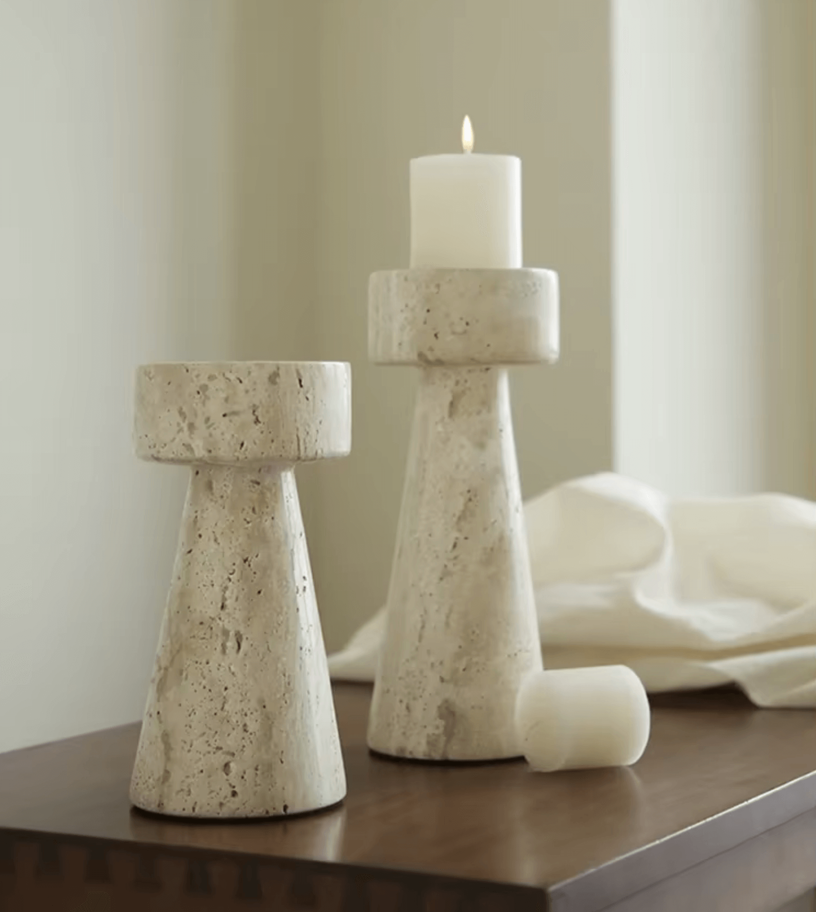 Naturmarmor-Kerzenhalter aus Travertin auf einem Tisch, rechteckig, mit einem brennenden weißen Kerzen, minimalistisch dekoriert.
