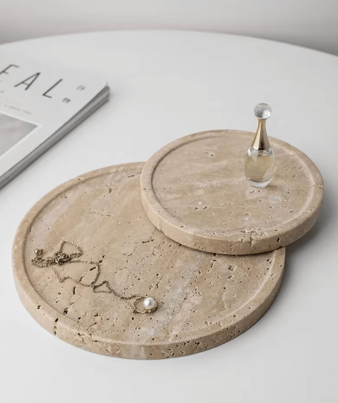 Handcrafted travertine marble trays with jewelry and perfume on a white surface, showcasing minimalist elegance.