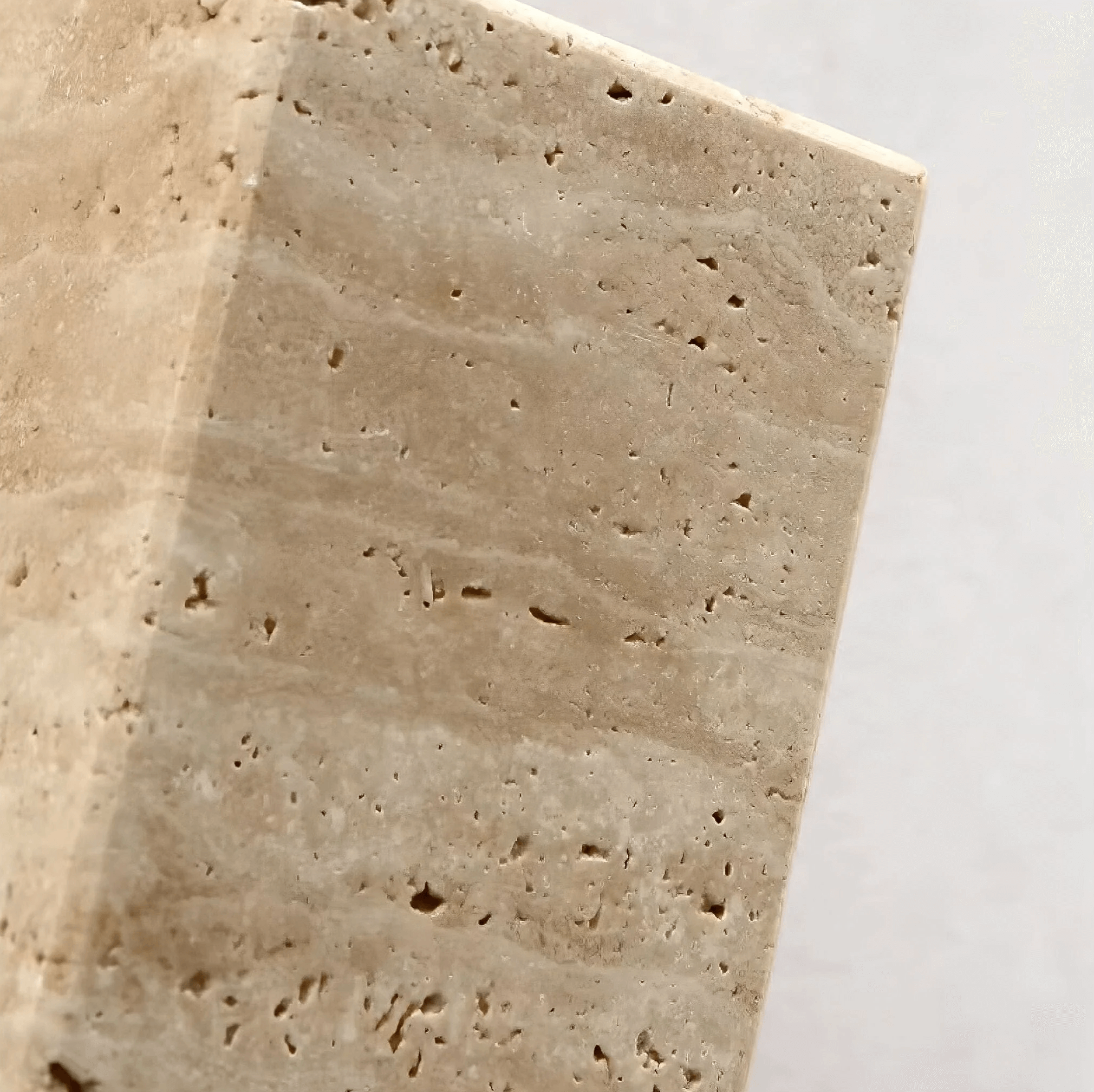 Close-up of beige travertine stone texture used in Wabi-Sabi wall lamp design