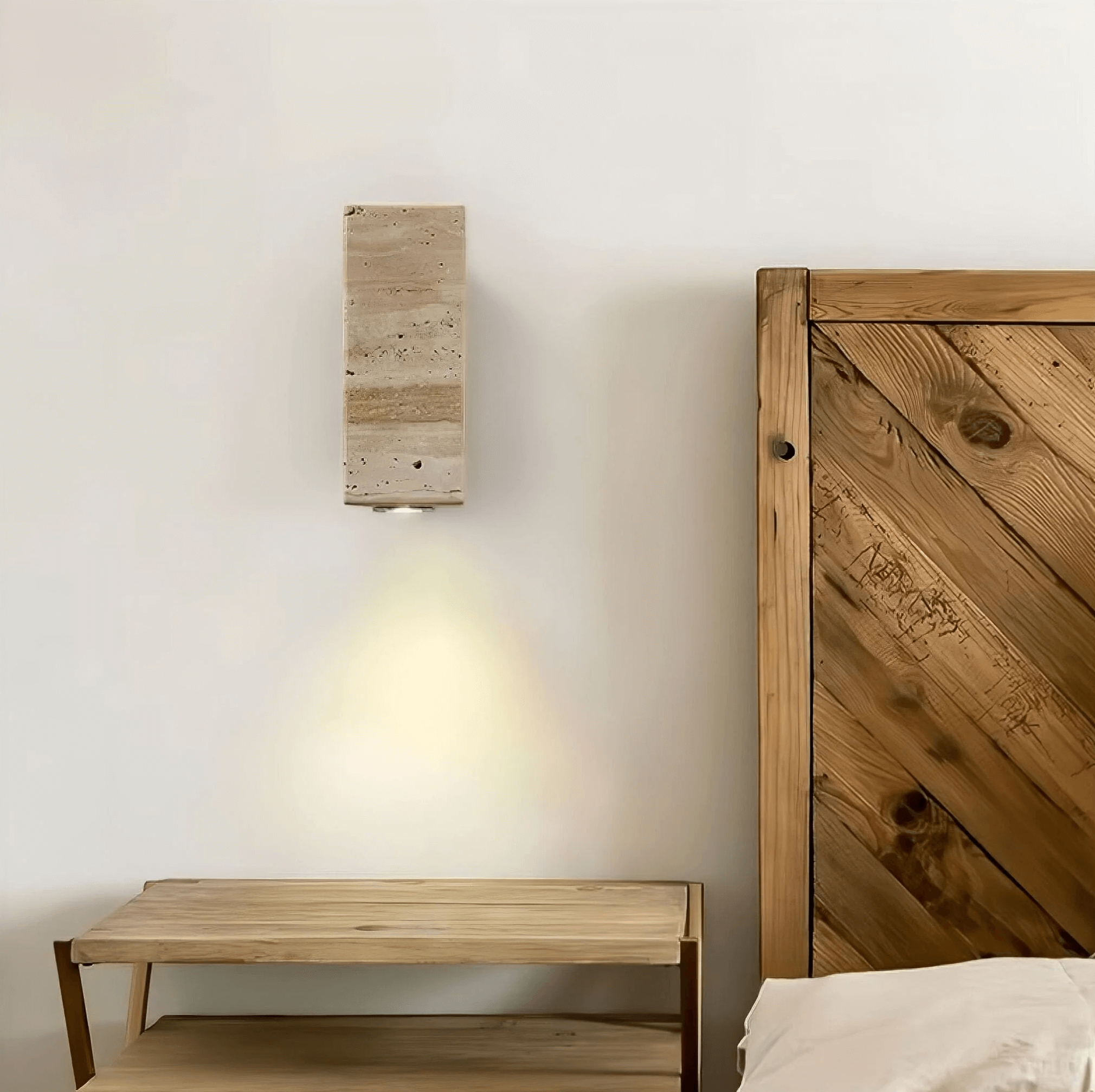 Wabi-Sabi Naturstein-Wandlampe aus Travertinstein und Aluminium, beige, neben einem Holzbett, verleiht dem Raum eine beruhigende Atmosphäre.