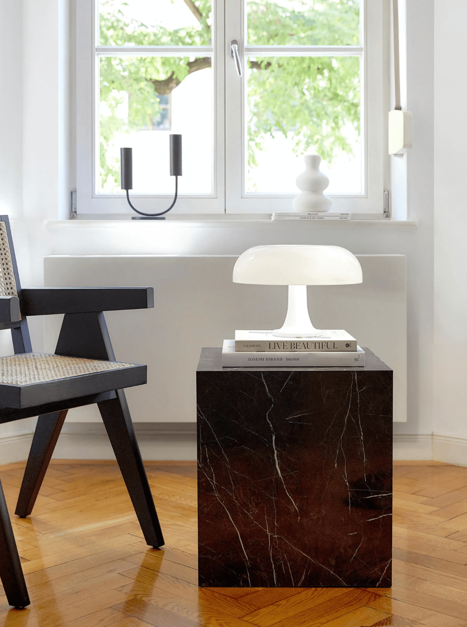 Interior with Bauhaus-style mushroom lamp on a black marble table beside a modern chair, showcasing timeless design and functionality.
