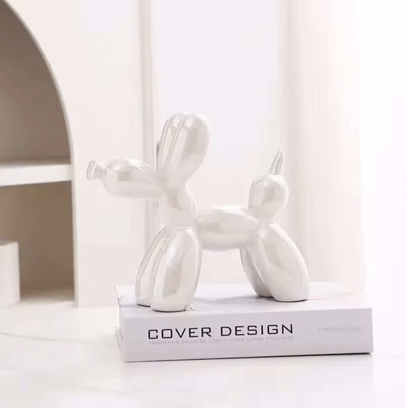 Silberne Keramik Ballonhund-Skulptur auf einem Designbuch in modernem Interieur.
