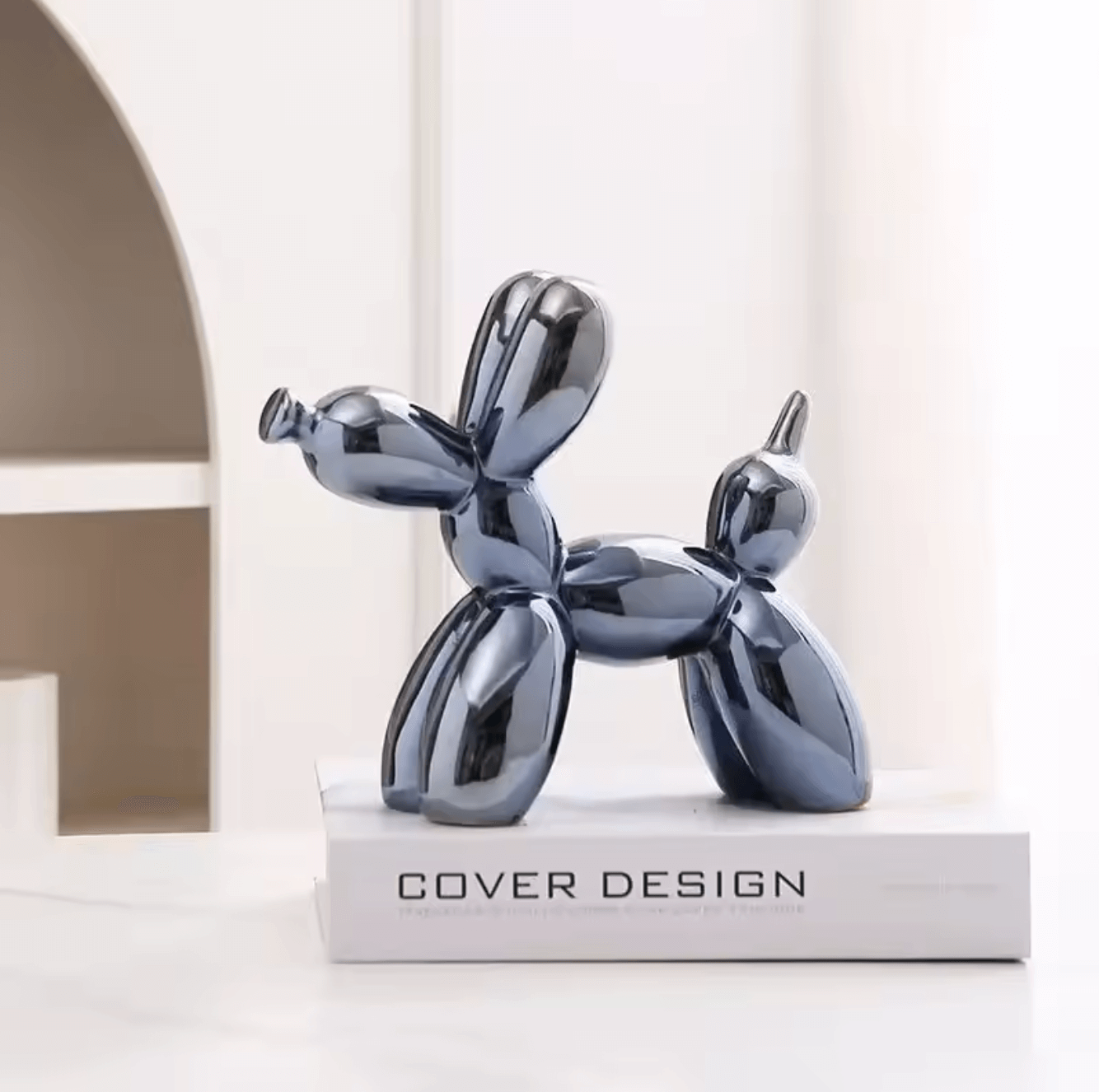Ceramic balloon dog sculpture in shimmering deep blue on a book