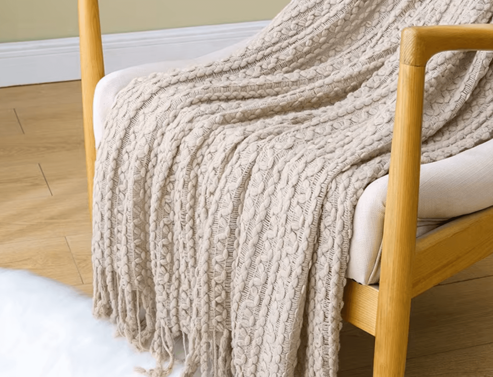 Boho Strickdecke mit Quasten aus beigem Strick, drapiert über einem Holzstuhl, ideal für gemütlichen Vintage-Charme zu Hause
