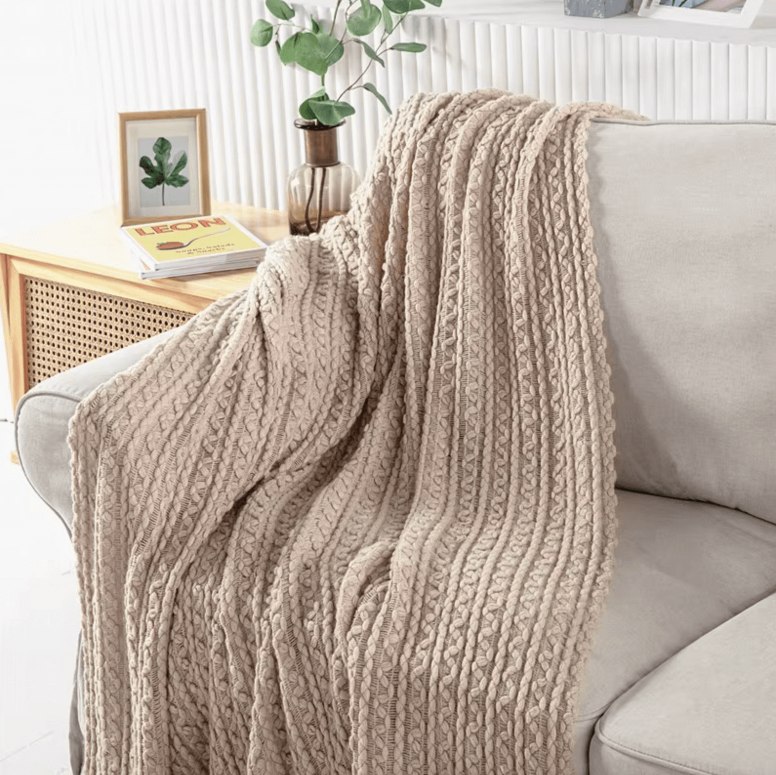 Boho knit blanket with tassels draped over a beige sofa, showcasing a timeless vintage design in cozy, neutral tones.