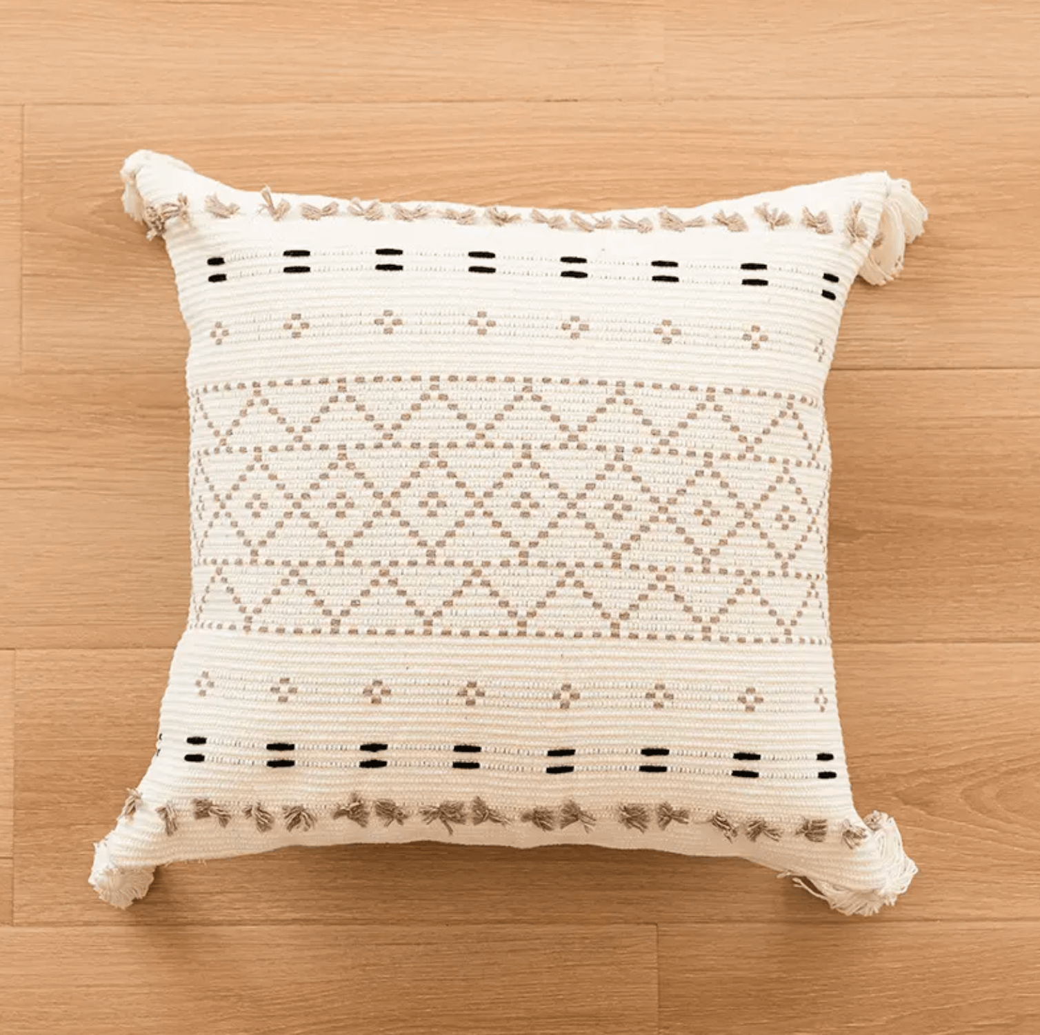 Boho Kissenbezug mit Diamantmuster in Beige mit Quasten, handgefertigt aus Baumwolle, auf hellem Holzboden