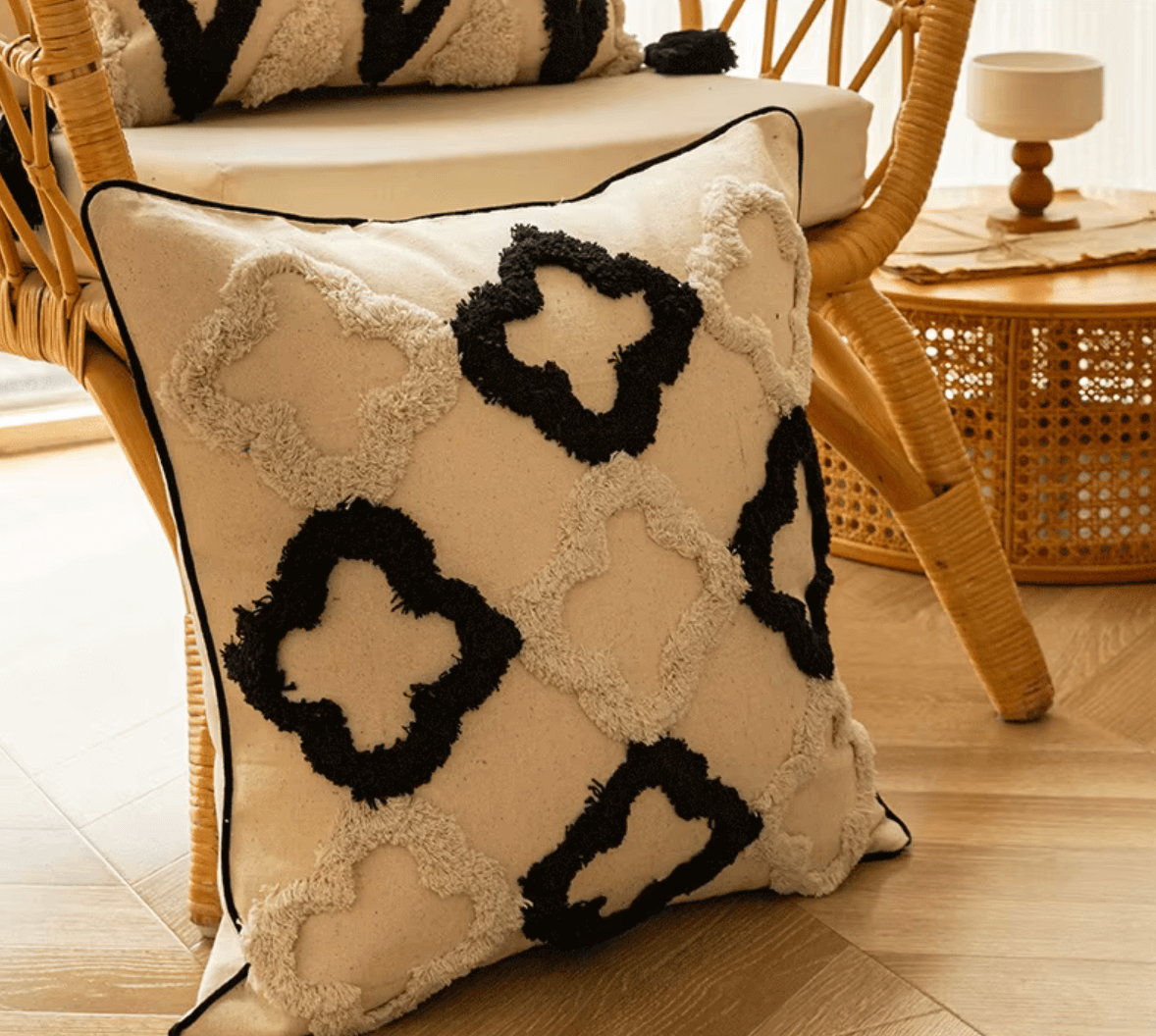Boho Kissenbezug mit schwarzem und weißem geometrischem Gitter-Design auf Flanellstoff, dekoriert auf einem Rattanstuhl im Wohnzimmer.