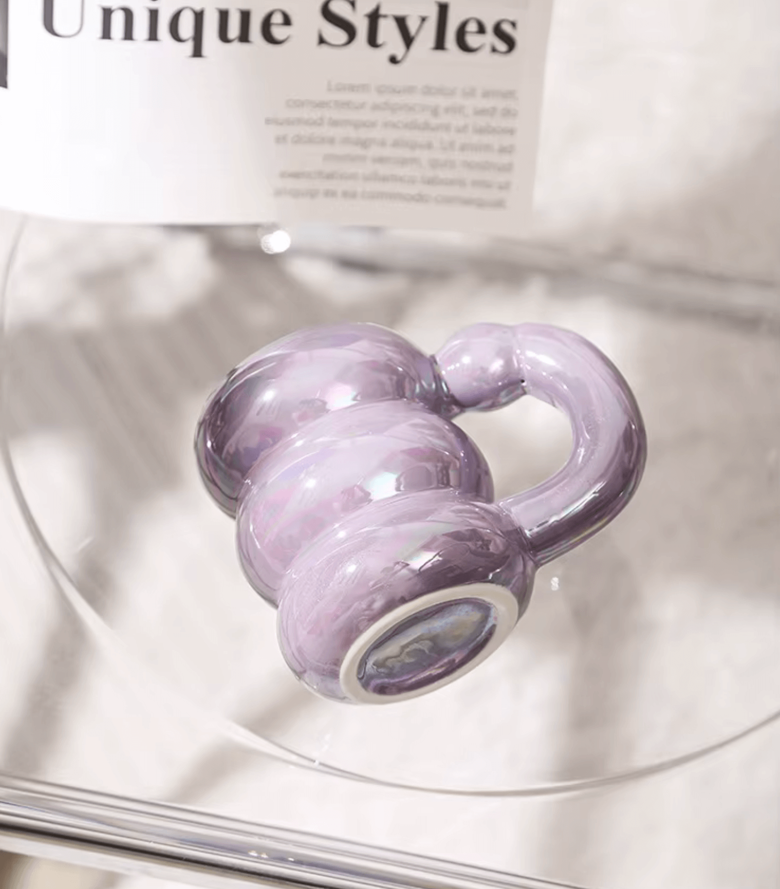 Pastel purple modern glass mug on a table with a newspaper in the background.