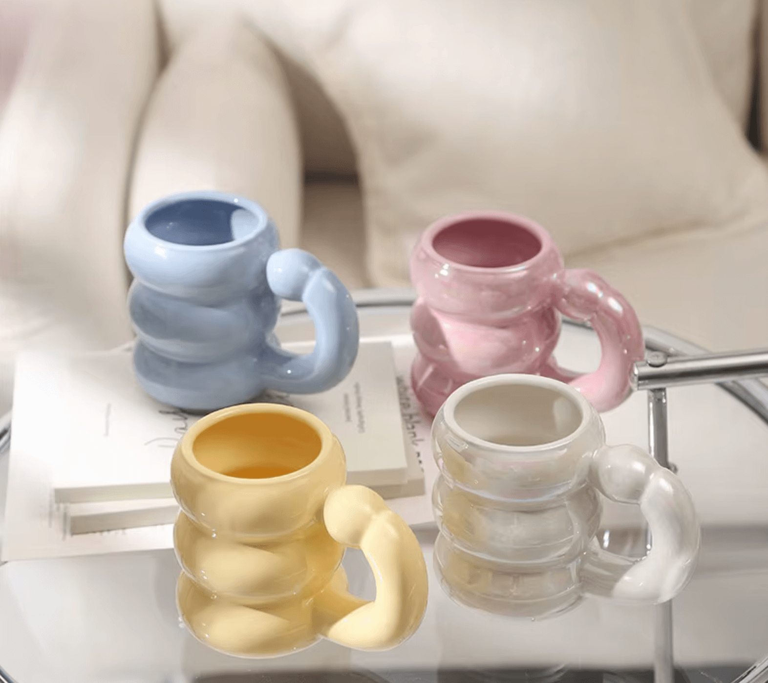 Set of four colorful mugs in Korean design on a modern table, showcasing blue, pink, yellow, and white hues.