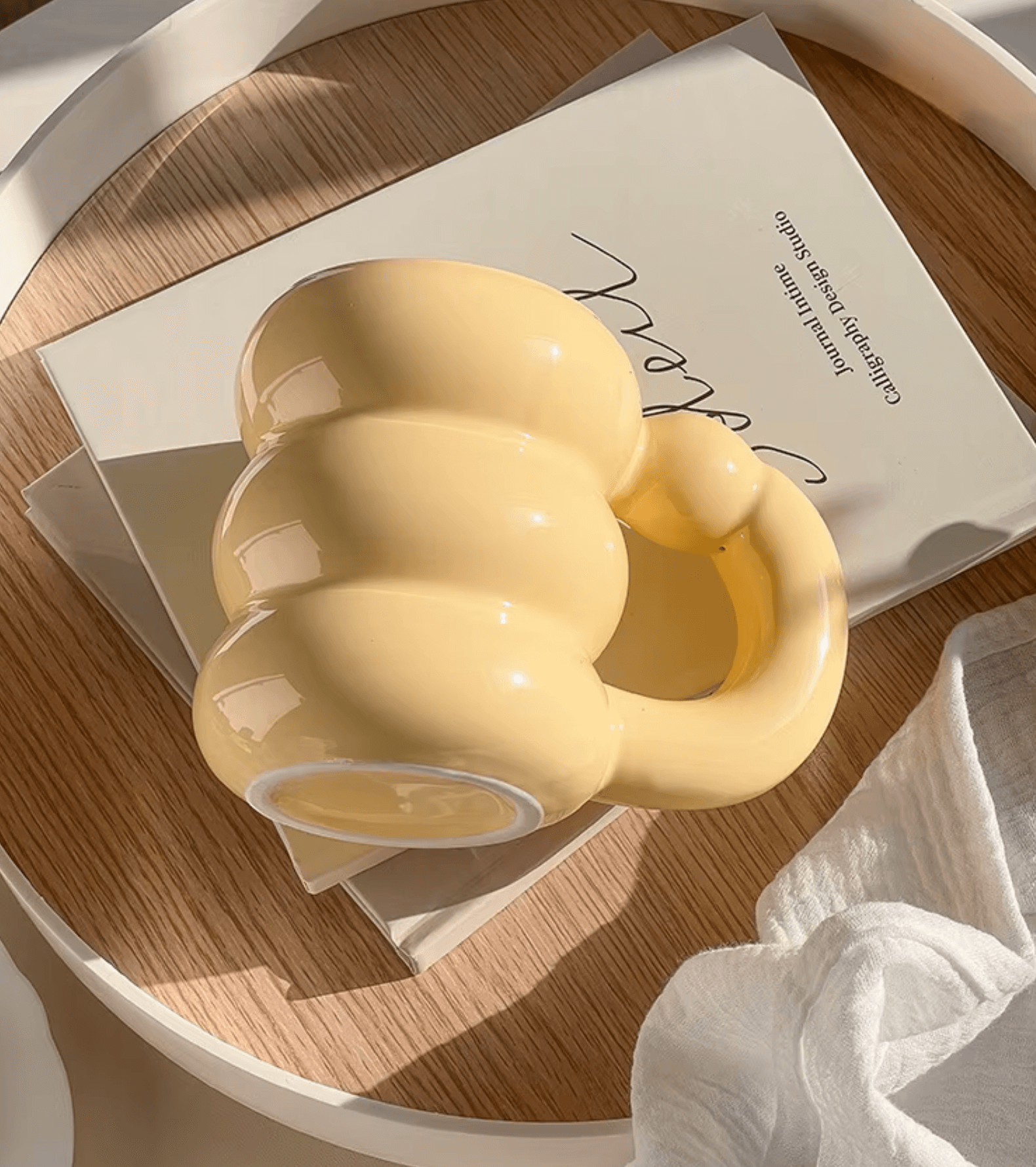 Gelbe Spring Bloom Tasse im koreanischen Design auf einem Buch, stilvolles Kaffeevergnügen.