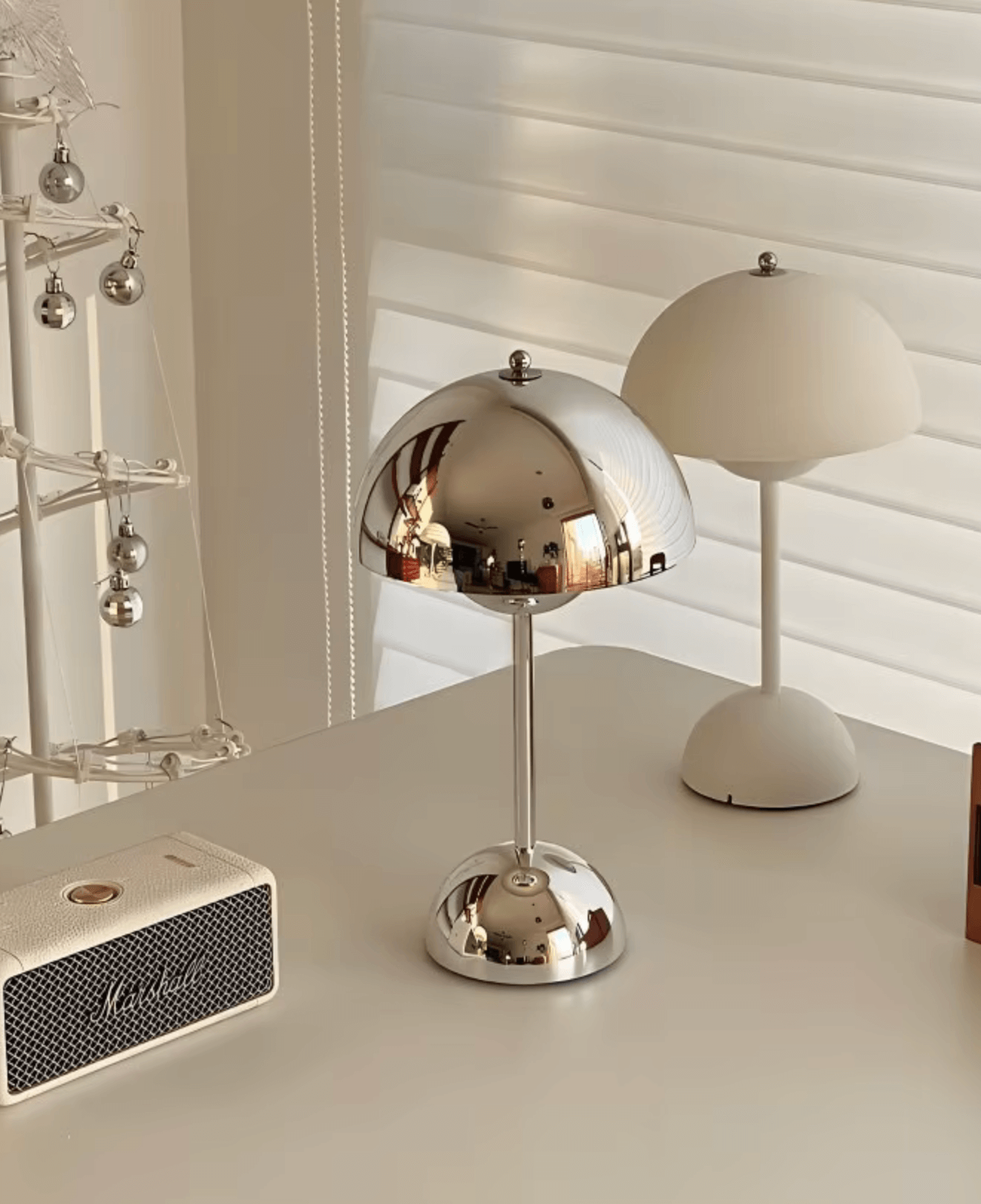 Chrome and white lamps on white desk with modern decor.