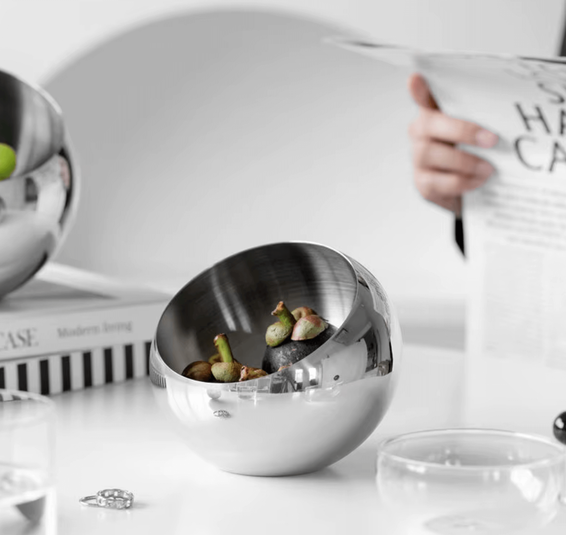 Modern stainless steel bowl with a minimalist design, ideal for stylishly displaying fruits or snacks on a white tabletop.