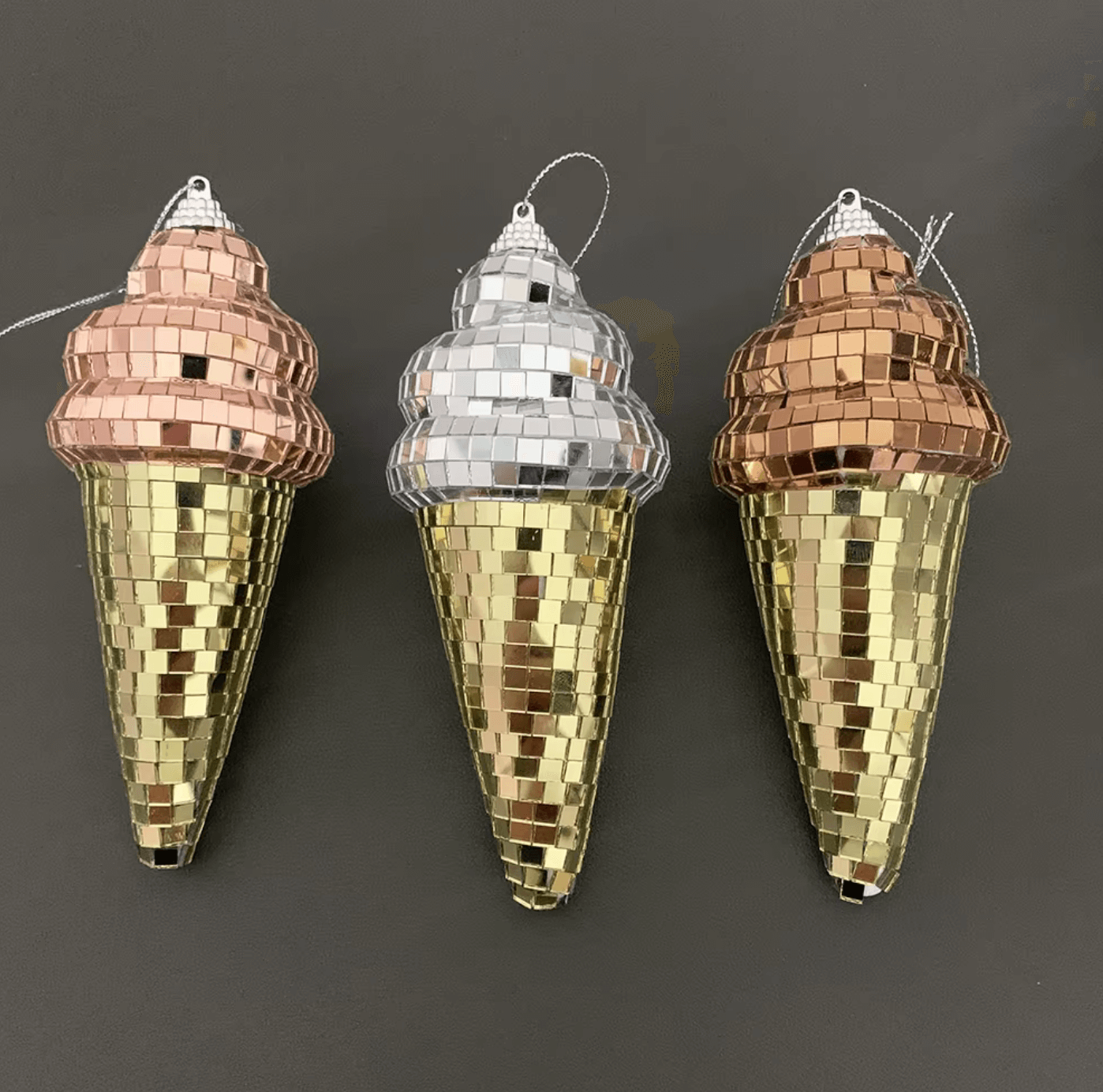 Three disco ice cream cone ornaments with mirrored tiles on a dark background, featuring a mix of gold, rose gold, and silver colors.