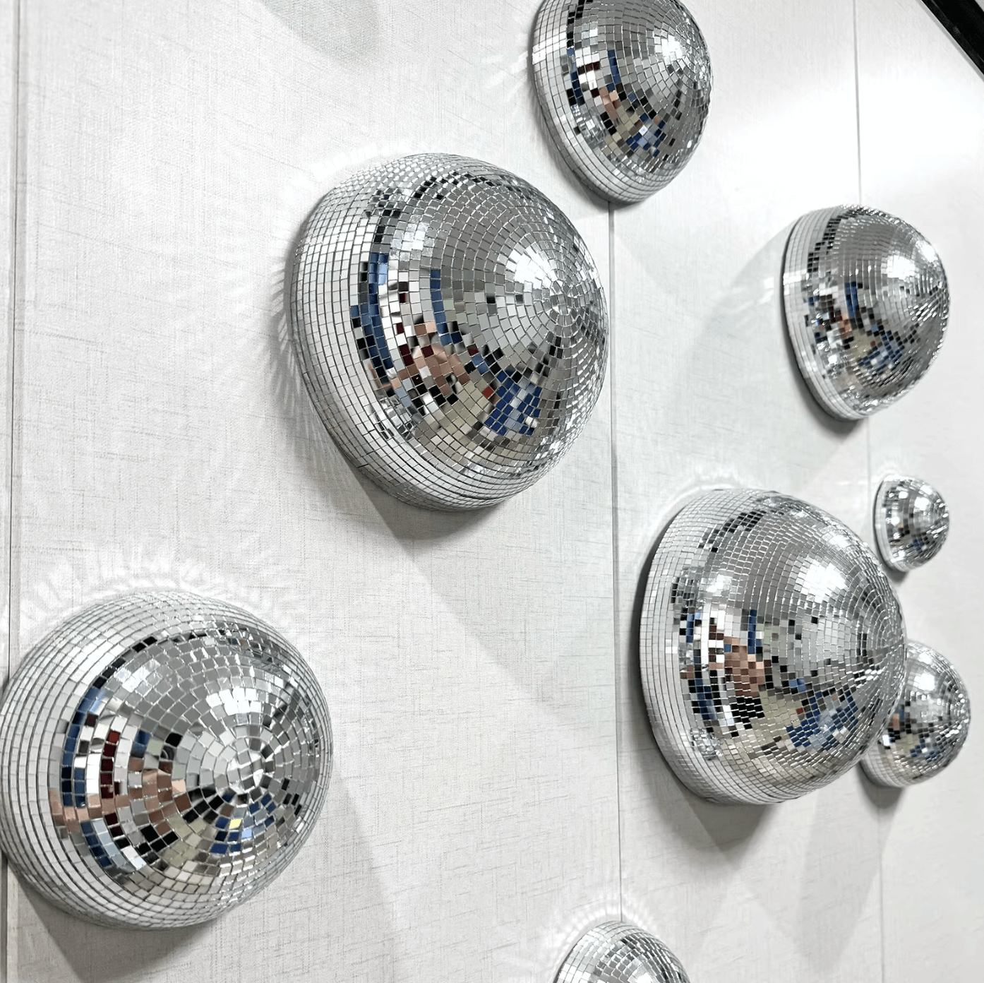 Disco-Kugel Wanddeko mit glitzernden Spiegeln auf weißer Wand, erzeugt Retro-Vibes und modernen Glamour für dein Zuhause.