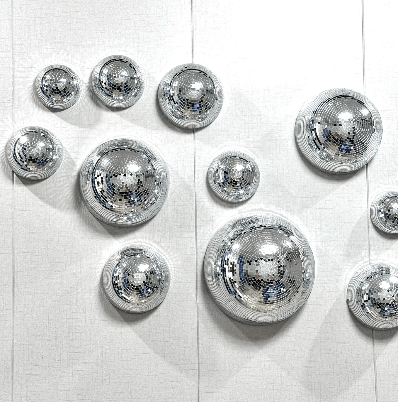 Disco-Kugel Wanddeko mit funkelnden Glaspailletten, bringt Retro-Vibes und Glamour an die Wand, hochwertiges Design in Halbkreisform.