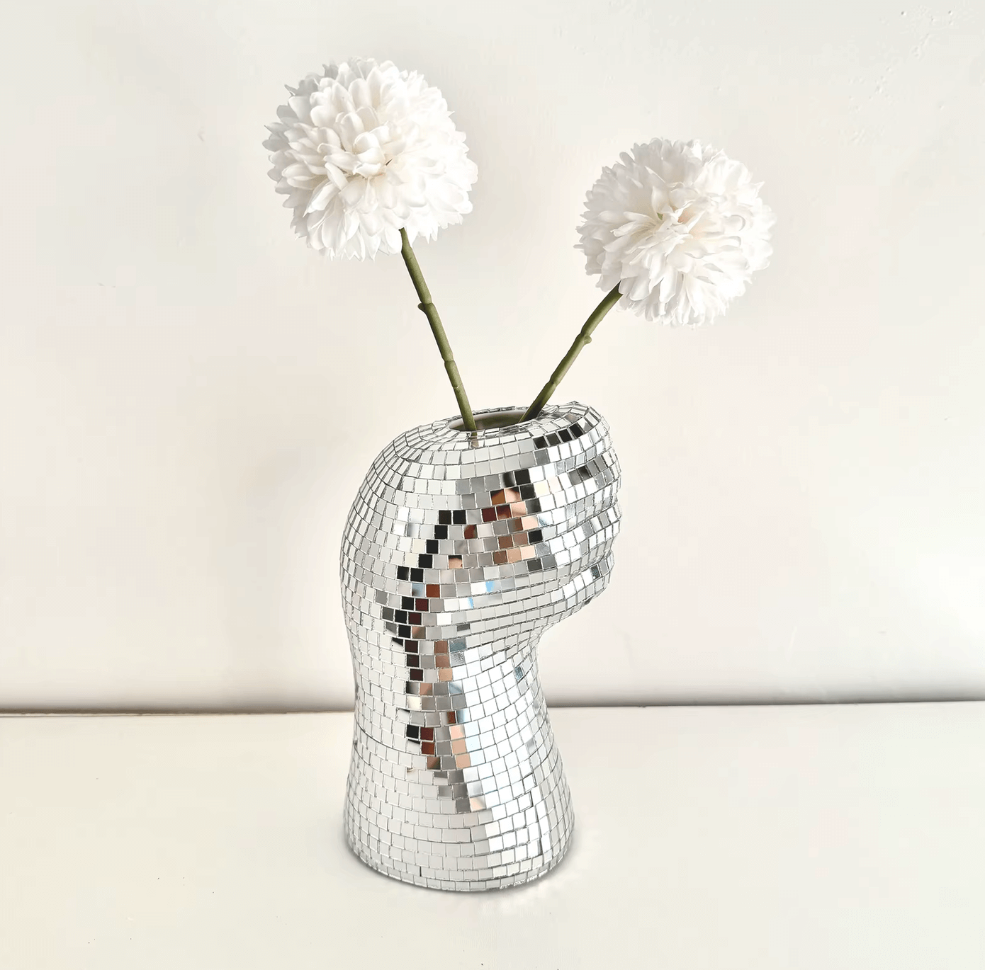 Silberne Disco-Handvase aus Spiegelglasfliesen mit zwei weißen Blumen, Retro-Design-Statement für stilvolle Wohnkultur.
