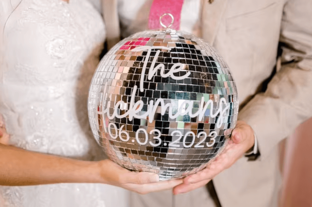Person holding a personalized disco ball with wedding date, perfect for parties and events, featuring mirrored mosaics and custom text.