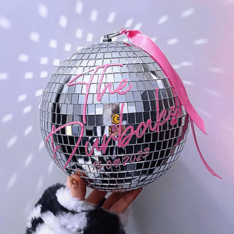 Personalisierte Disco-Kugel mit pinkem Schriftzug und Spiegelmosaiken für besondere Anlässe.