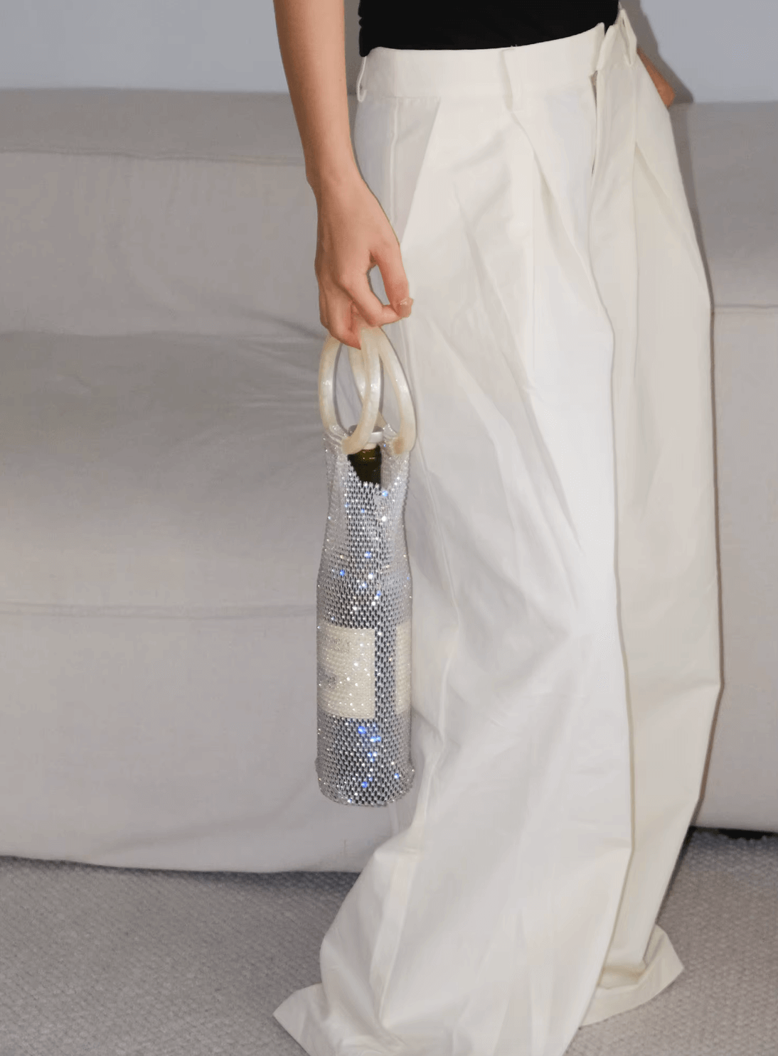 Person holding a luxurious handwoven wine bottle bag with diamond handle, showcasing elegant and stylish design.