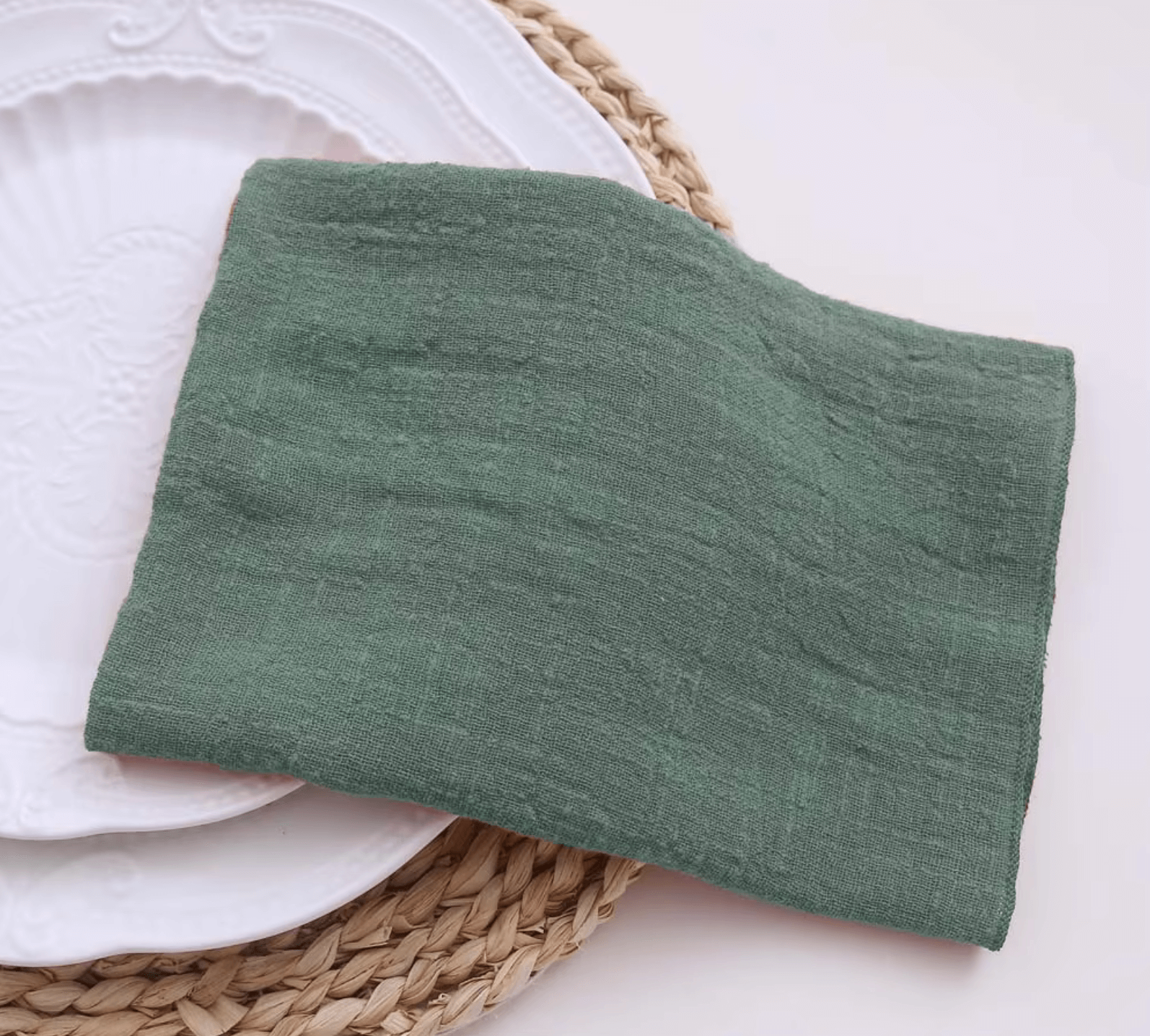 Green cotton napkin elegantly folded on a white plate, showcasing sustainable table decor.