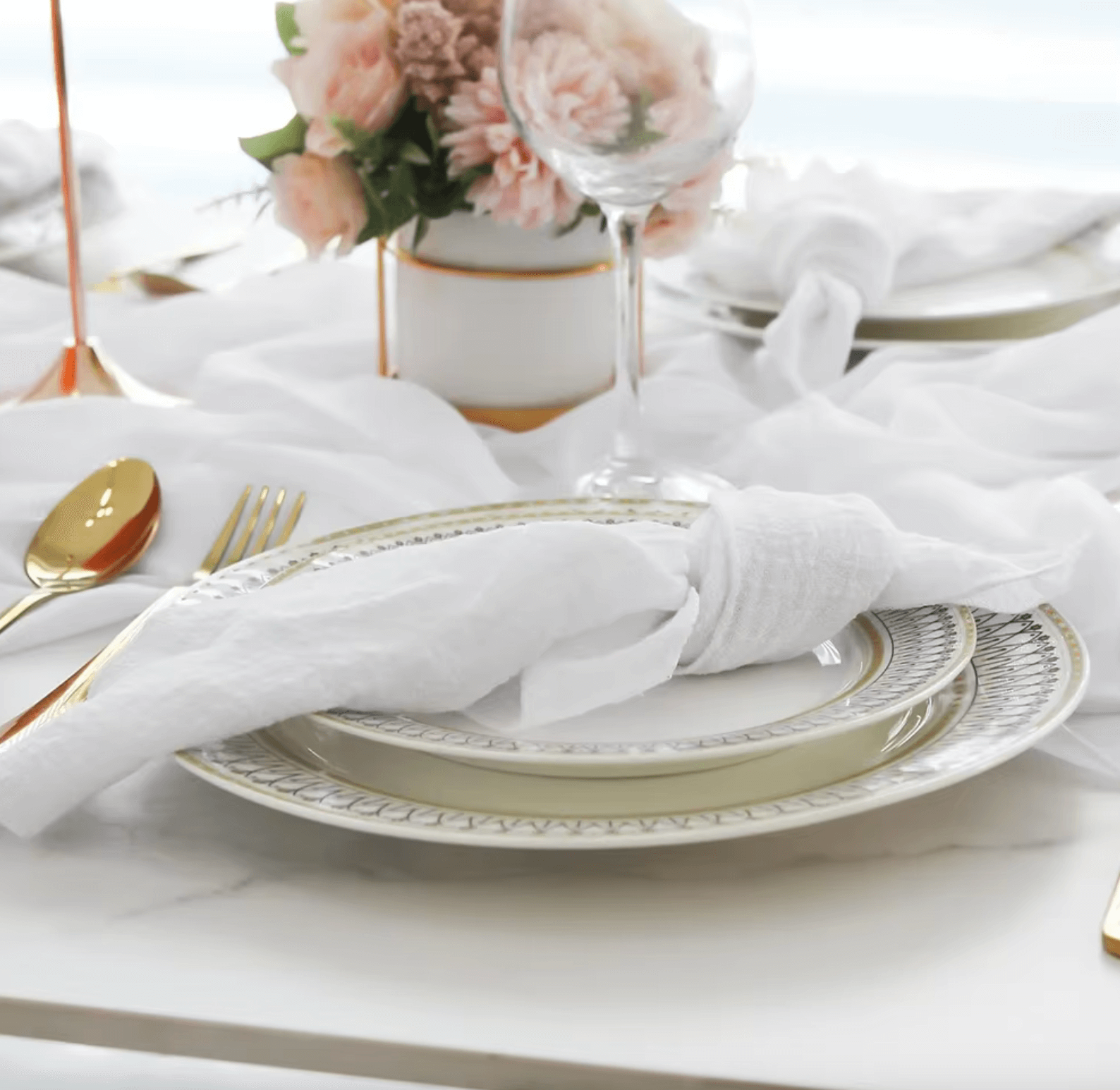 Elegant table setting with white cotton napkins, fine china, and floral centerpiece for a refined dining experience.