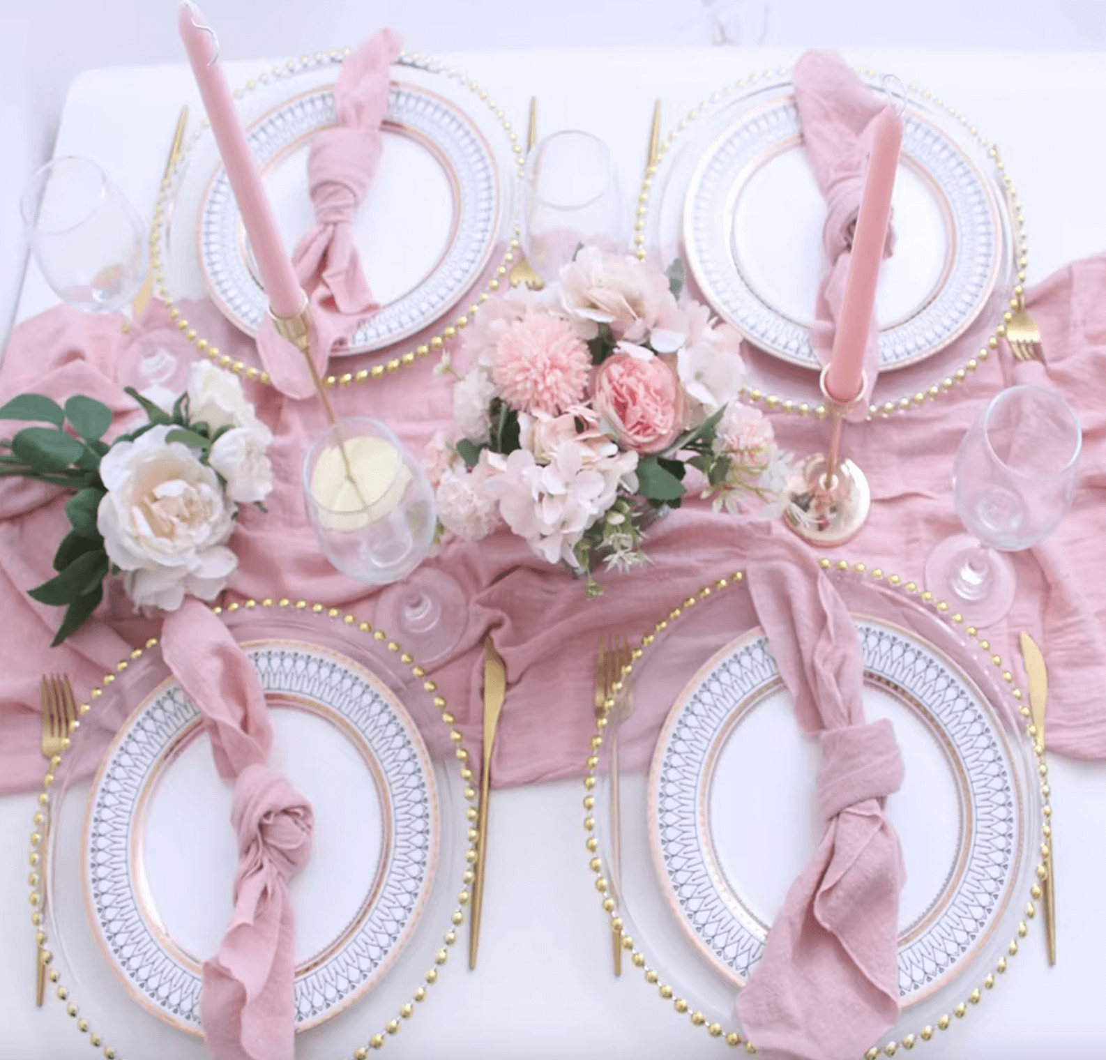 Elegant table setting with pink cotton napkins, floral centerpiece, and gold-accented plates, showcasing sustainable dining decor.