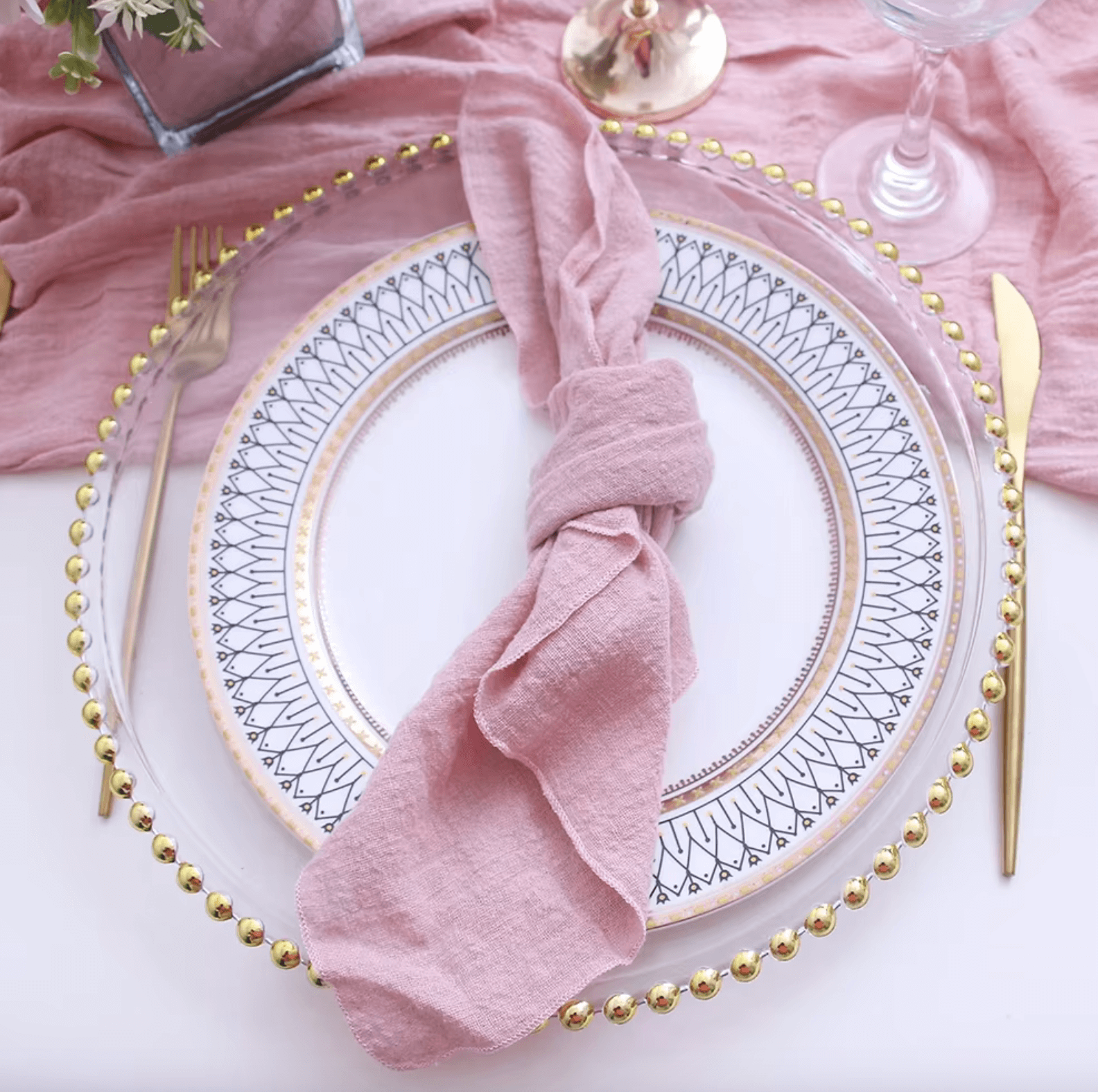 Elegant table setting with pink cotton napkin and decorative plate, highlighting sustainability and style for special occasions.