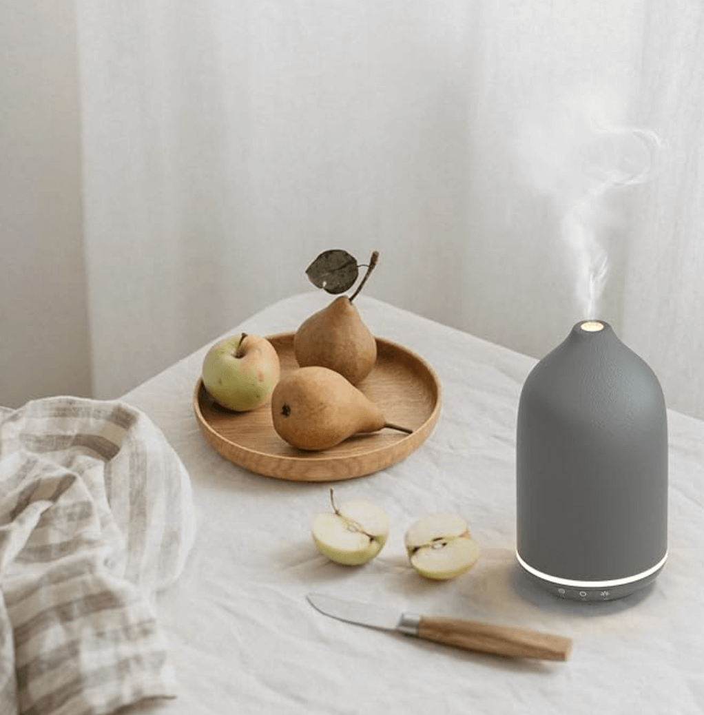 Ultraschall-Aromatherapie-Diffusor auf Tisch mit Obst, modernes Design für Entspannung zu Hause oder im Büro