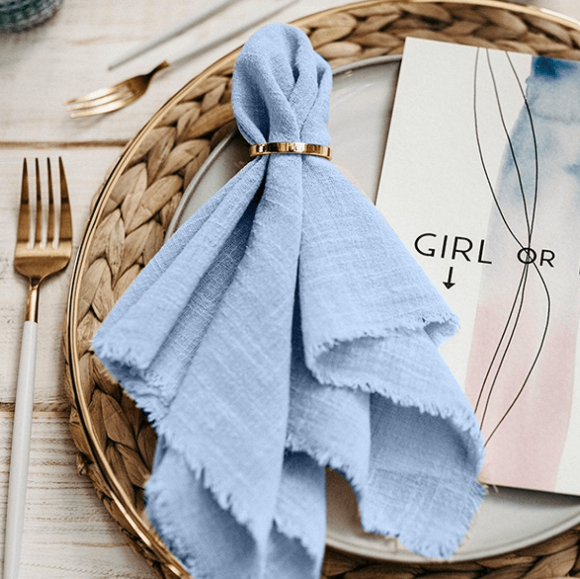 Goldene Serviettenringe auf blauem Tuch an festlichem Tisch. Elegante Tischdekoration in Gold & Silber für besondere Anlässe.