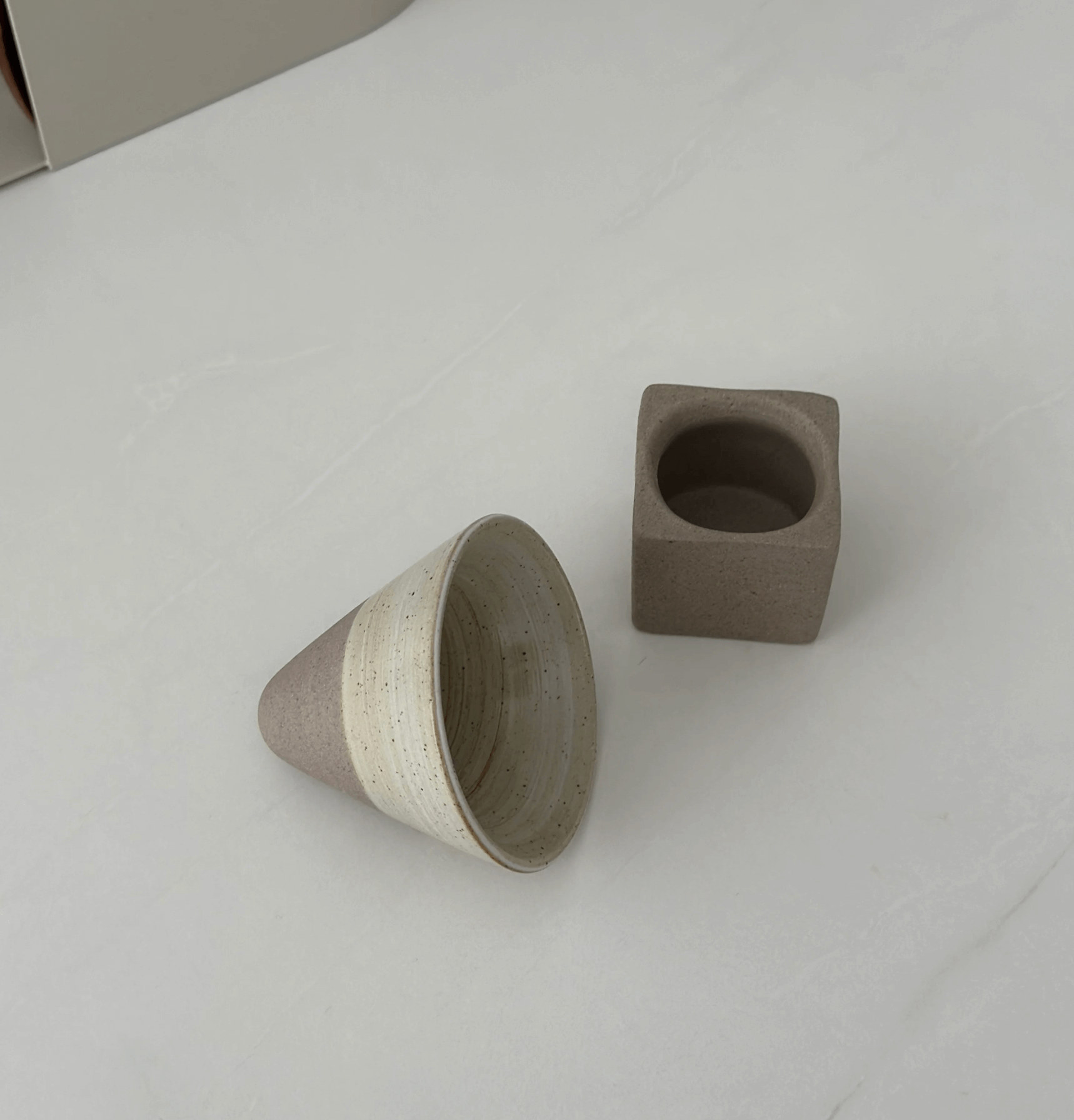 Japanische Keramik-Teetasse mit einzigartigem Design und Kegelform neben passendem Sockel, inspiriert von traditioneller Teekultur.