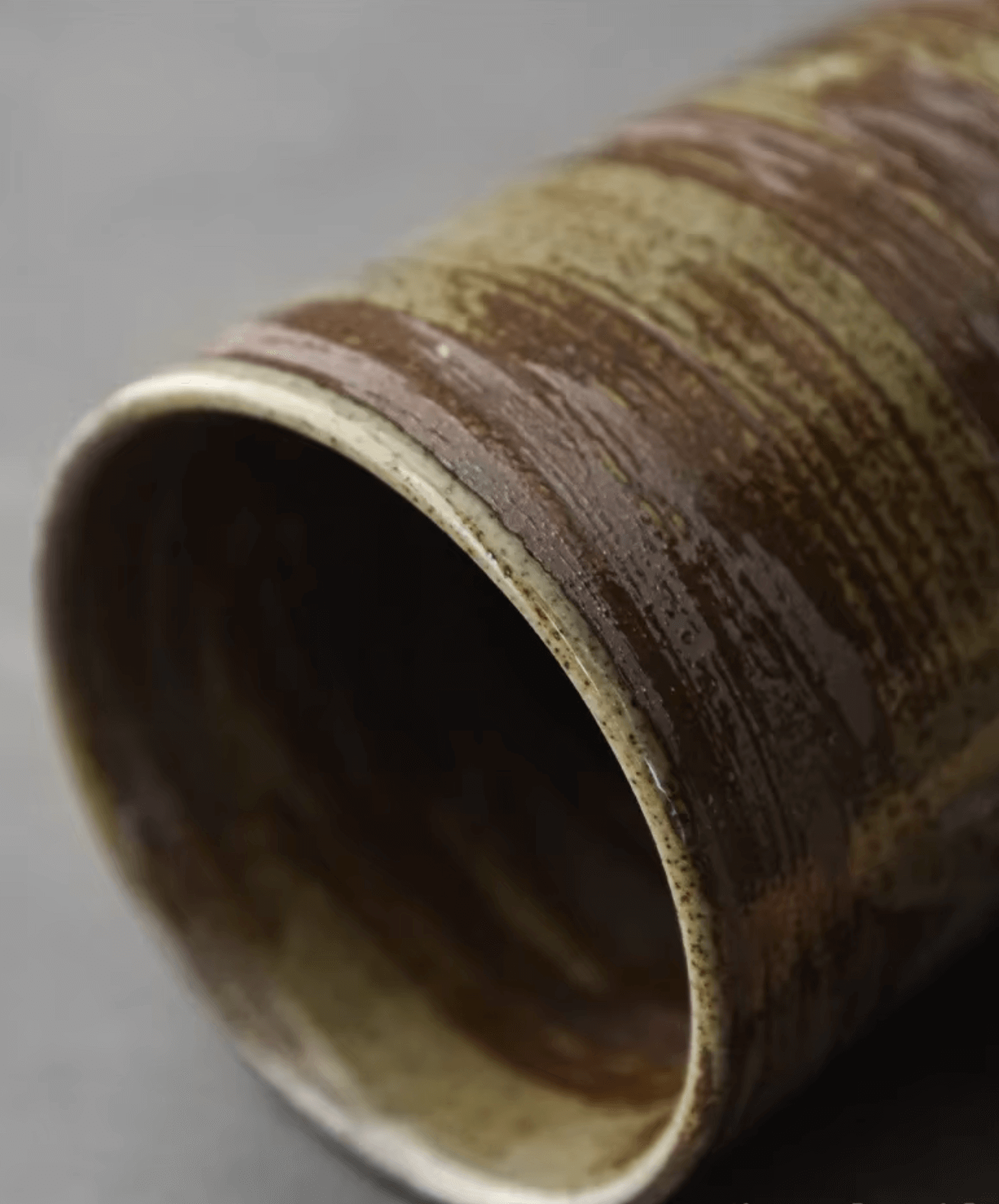 Close-up of a handmade ceramic coffee cup with a rustic brown glaze, highlighting its textured surface for a natural look.