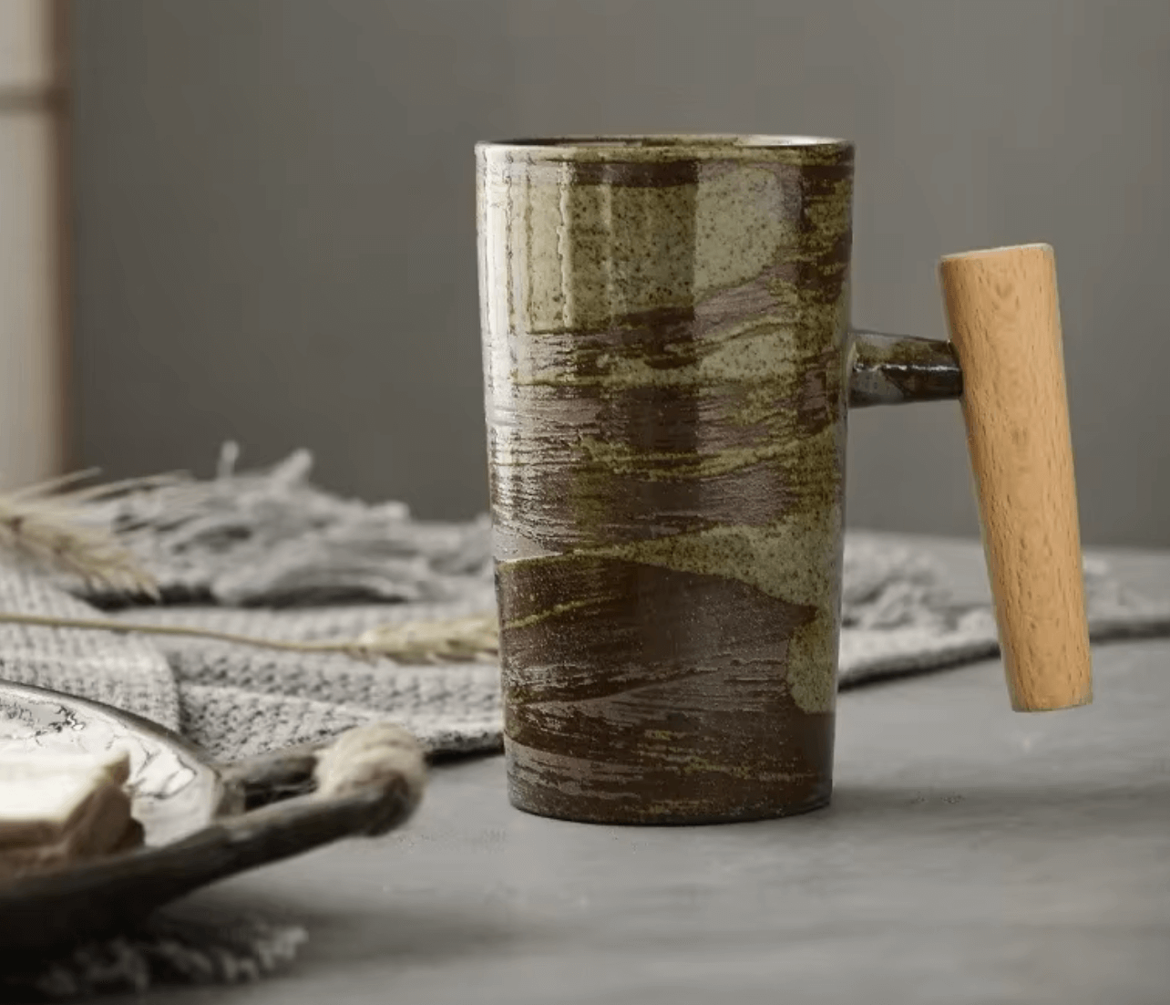 Keramik-Kaffeetasse mit Holzgriff auf einem Tisch, handgefertigt für rustikale Eleganz und moderne Funktionalität, ideal für Kaffee oder Tee.
