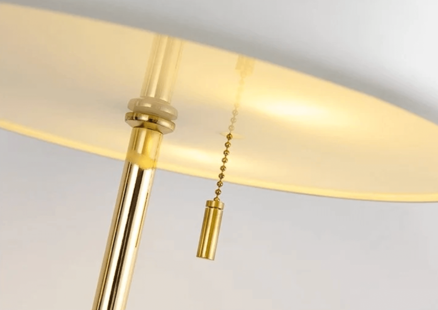 Close-up of Nordic Glow LED Tischlampe with gold accents and pull cord for adjustable lighting.