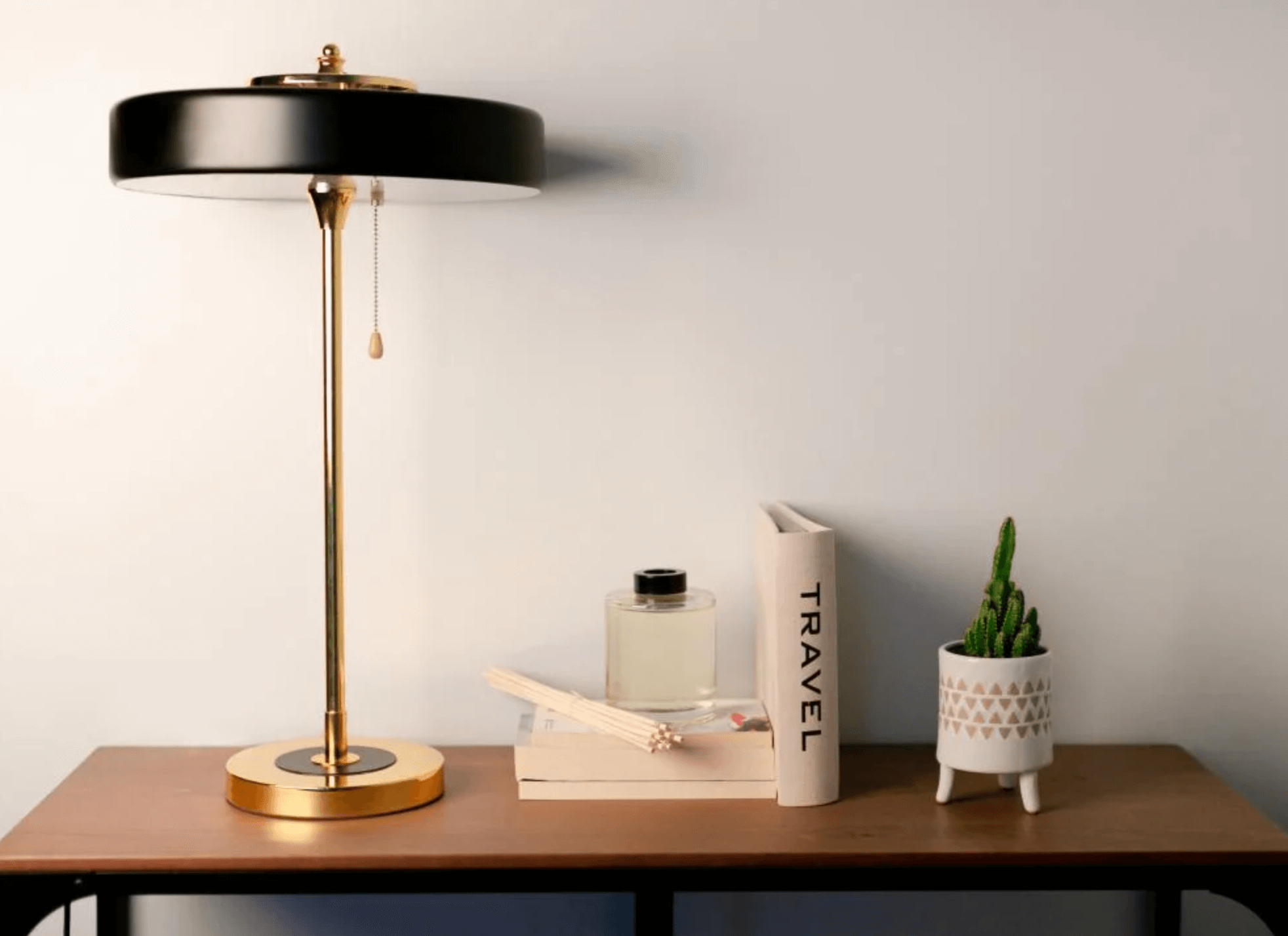 Nordic Glow LED Tischlampe with gold accents on a wooden desk, featuring a book, candle, and a small potted plant for home decor.