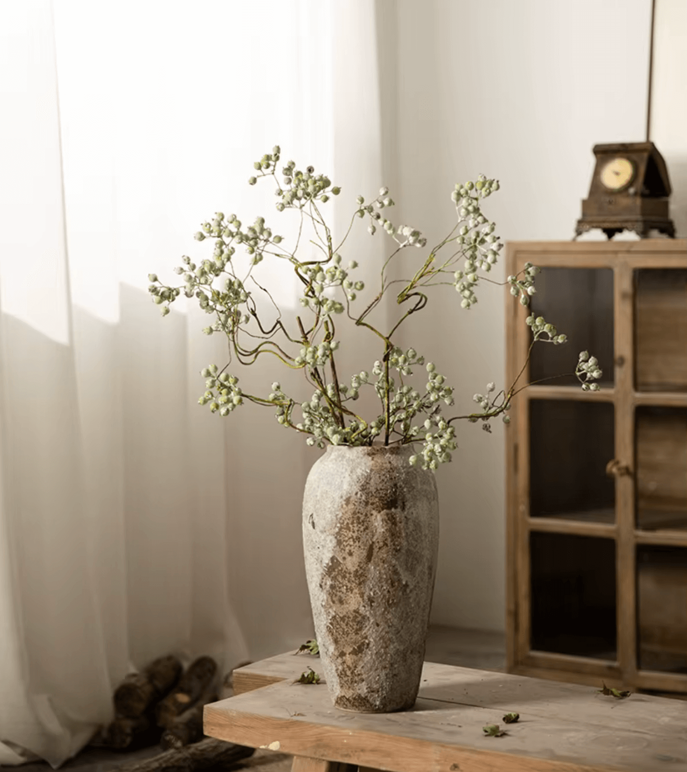 Handgefertigte rustikale Keramikvase im antiken Design mit Pflanzen, stehende Vase auf Holztisch vor Fenster, vintage Dekoration