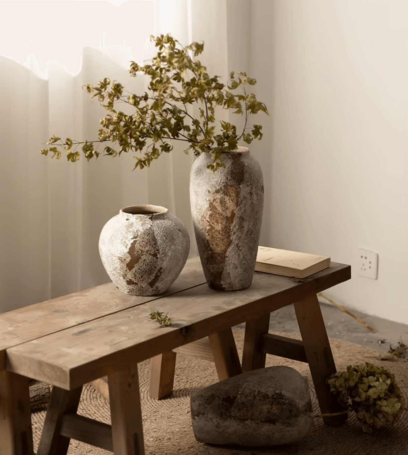 Rustikale Eleganz Handgefertigte Keramikvase im antiken Design, präsentiert auf einem Holztisch mit grünen Zweigen, rustikales Finish.