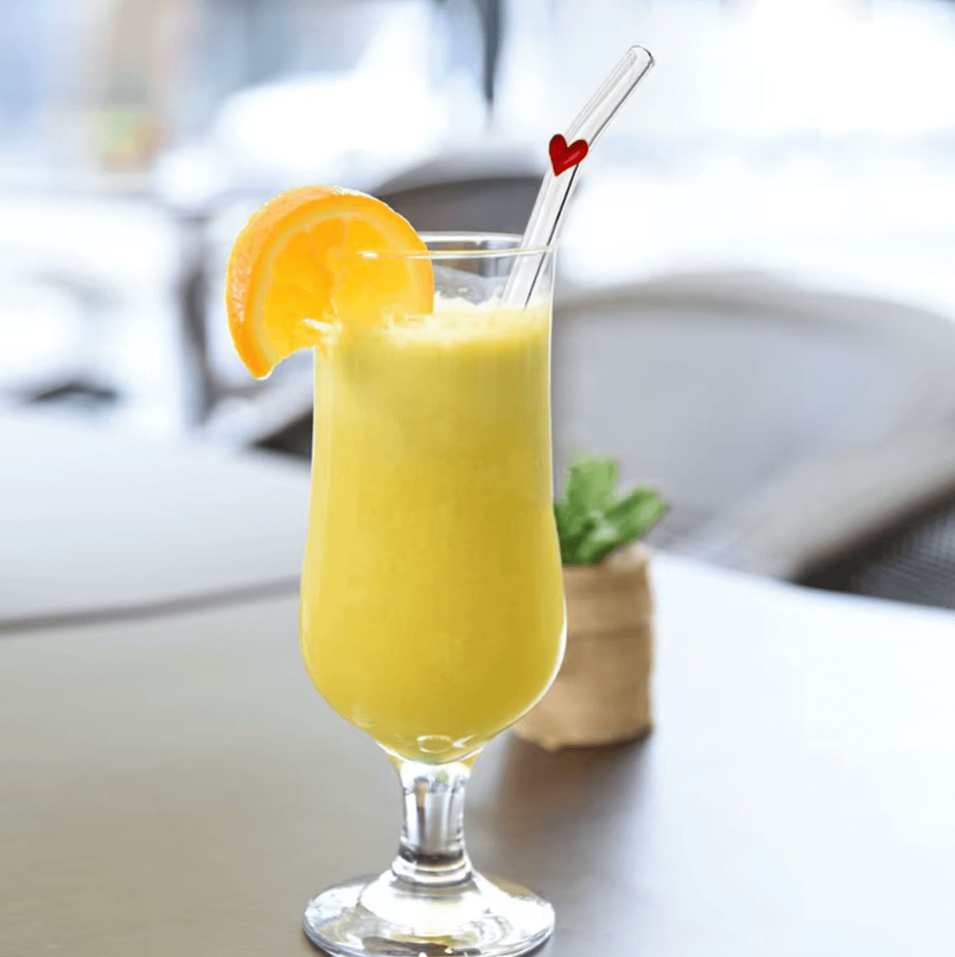 Fresh orange smoothie with a "Pure Sip" glass straw, perfect for eco-friendly and stylish enjoyment.