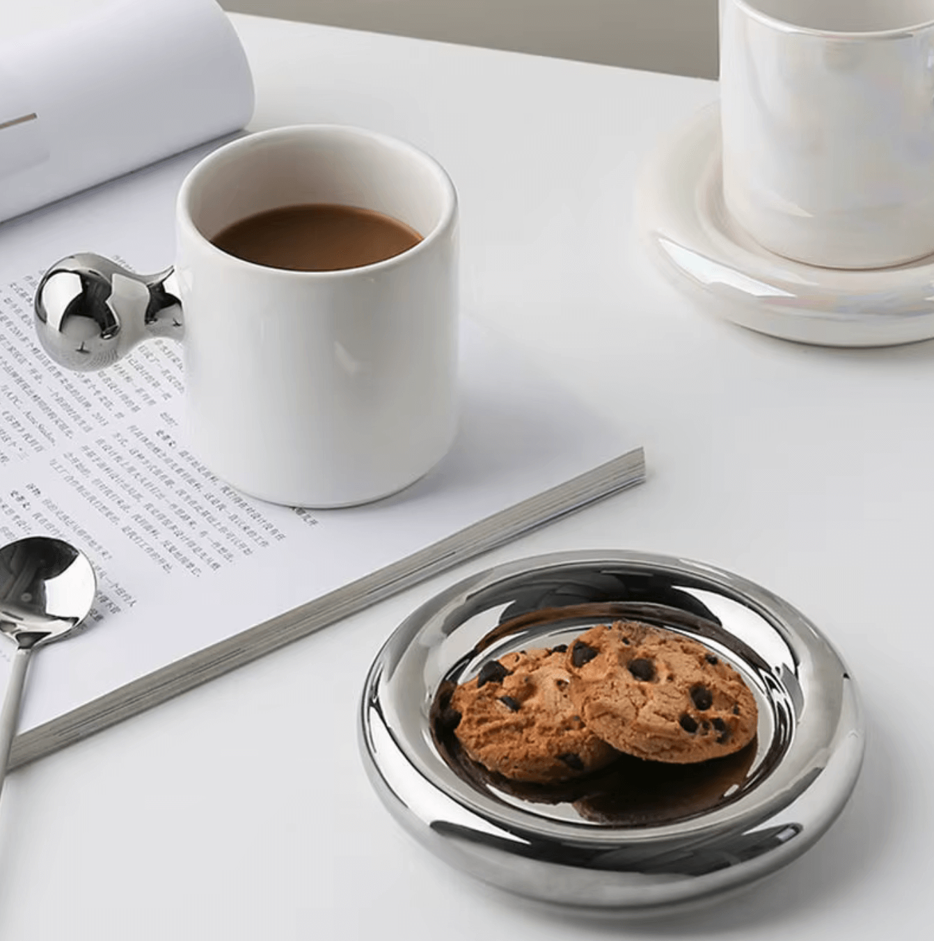 Nordic Elegance ceramic coffee set with cookies, minimalist Scandinavian design featuring silver details on a modern table.