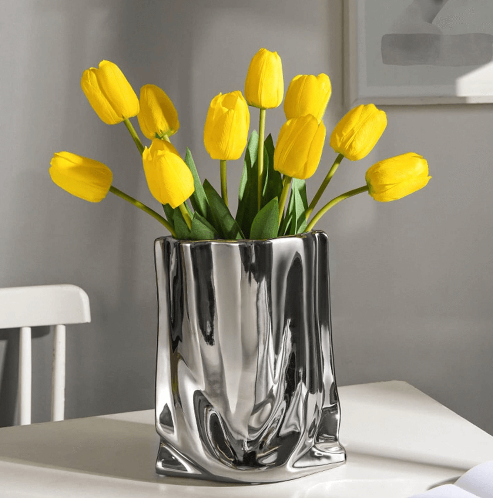 Silberne Blumenvase aus Keramik mit gelben Tulpen, stilvolle Dekoration für modernes Zuhause, glänzendes Design auf Tisch