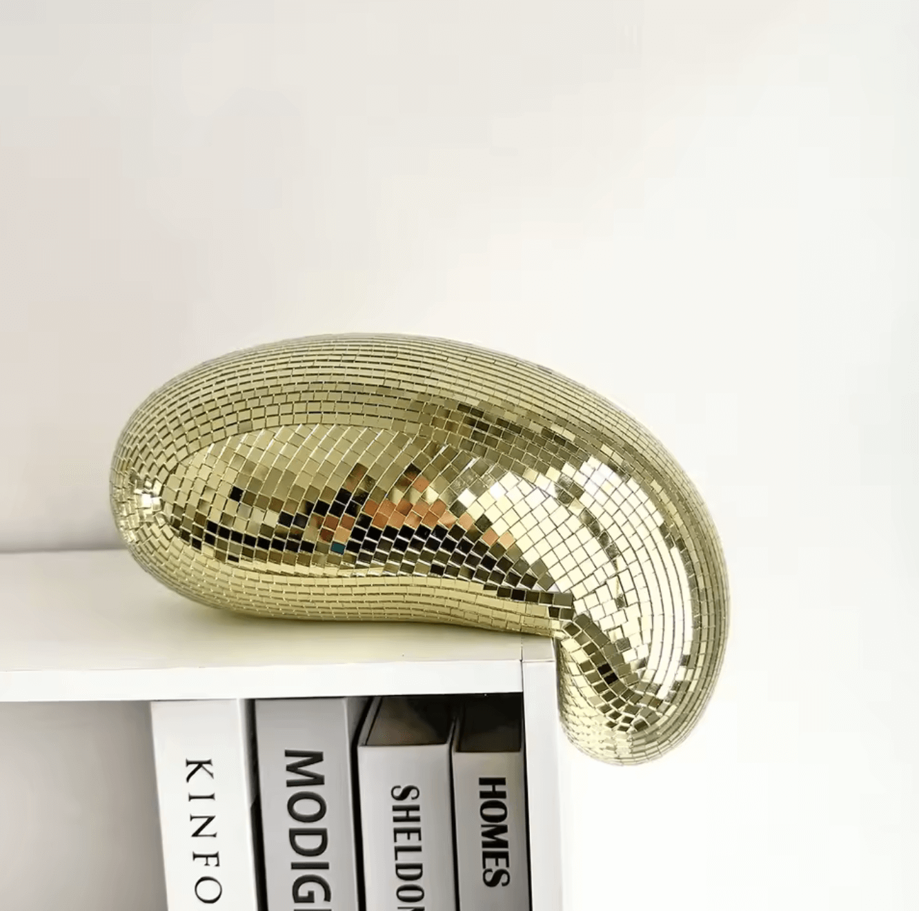 Stylish melting disco ball on bookshelf, featuring a unique flow design with mirror glass tiles for retro-glam home decor.