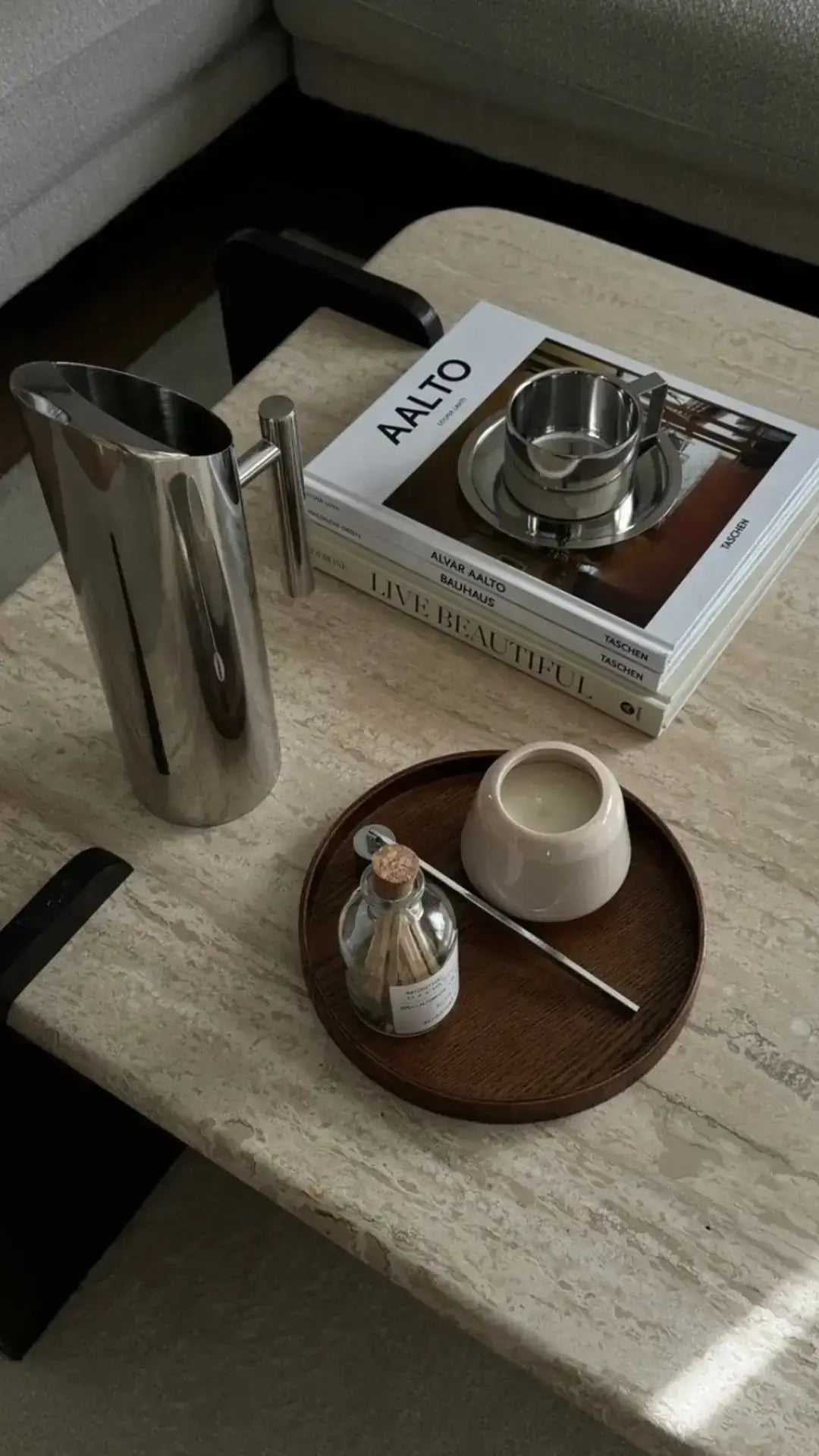 Stainless steel water jug on a table with books and a tray for modern home decor.