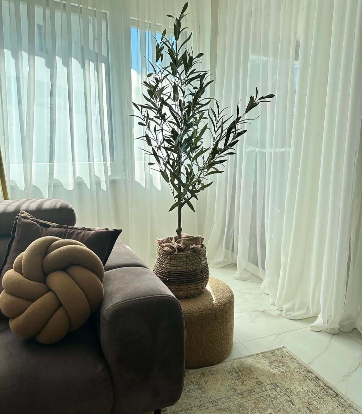 Artificial olive tree in a stylish living room, adding Mediterranean elegance without maintenance. Perfect décor for any interior space.